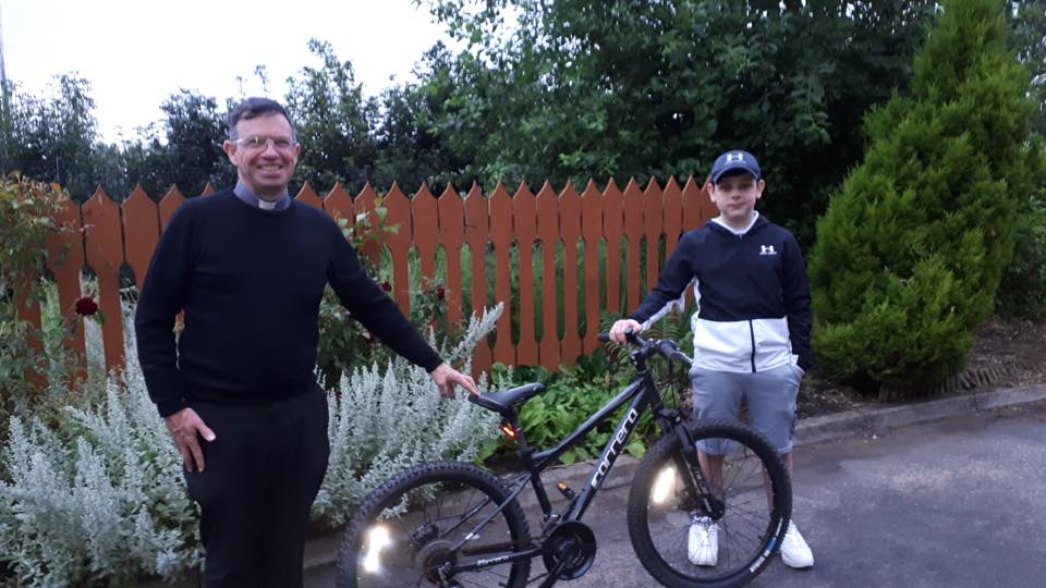 BIG HEART: Pearse Cordner-Reilly hands his bike over to Fr Magill