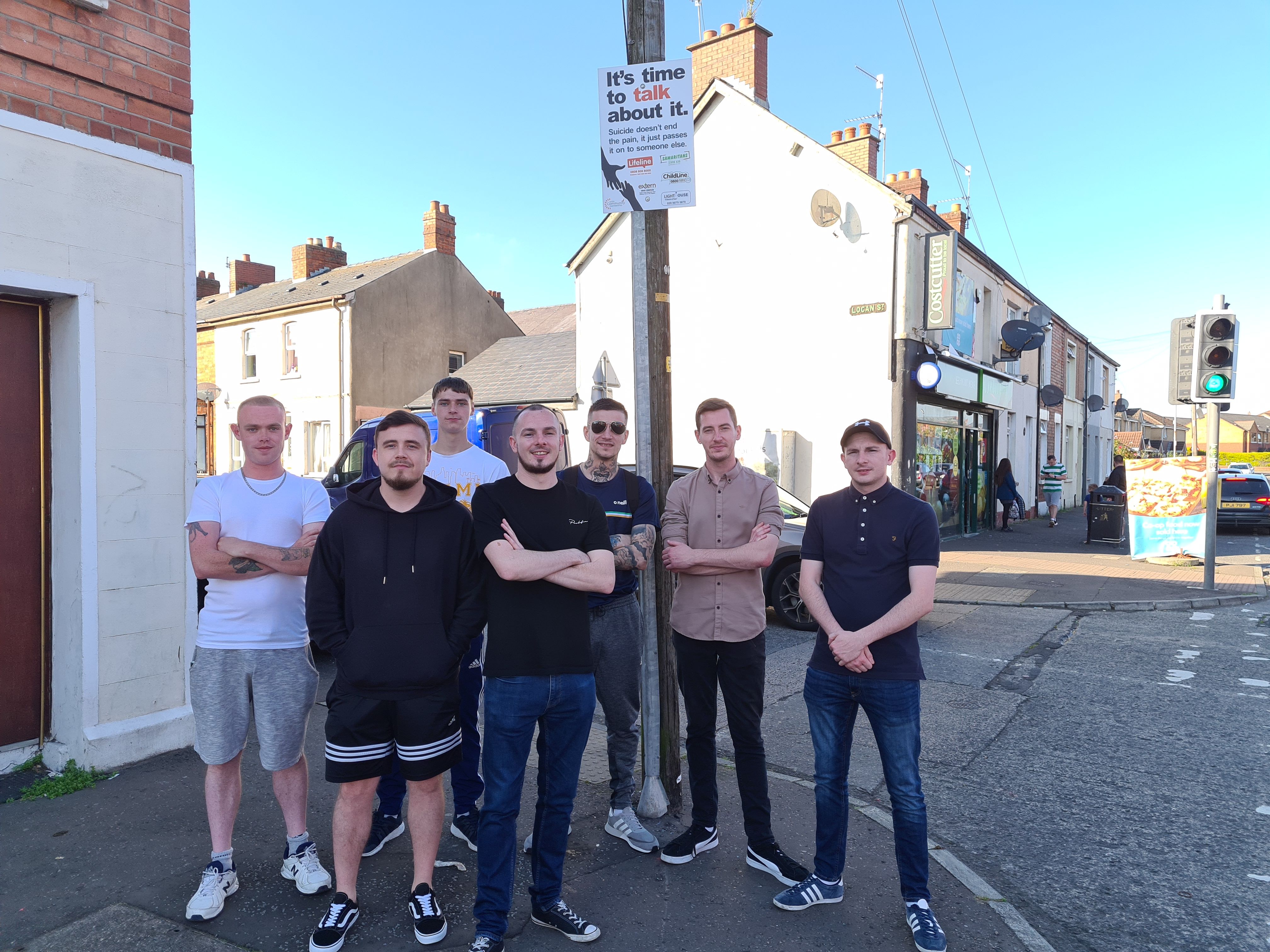 WALK AND TALK: Members of the Beechmount Residents’ Collective standing under one of their posters