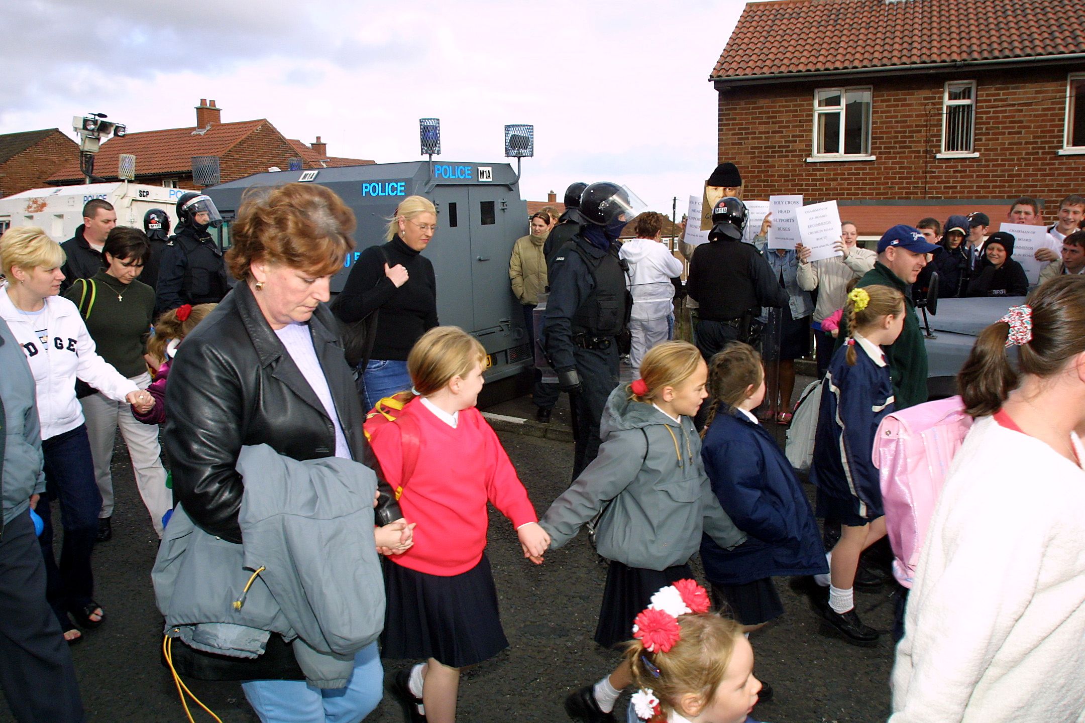 RUNNING THE GAUNTLET: Parents and children are escorted to Holy Cross Girls\' Primary School in 2001