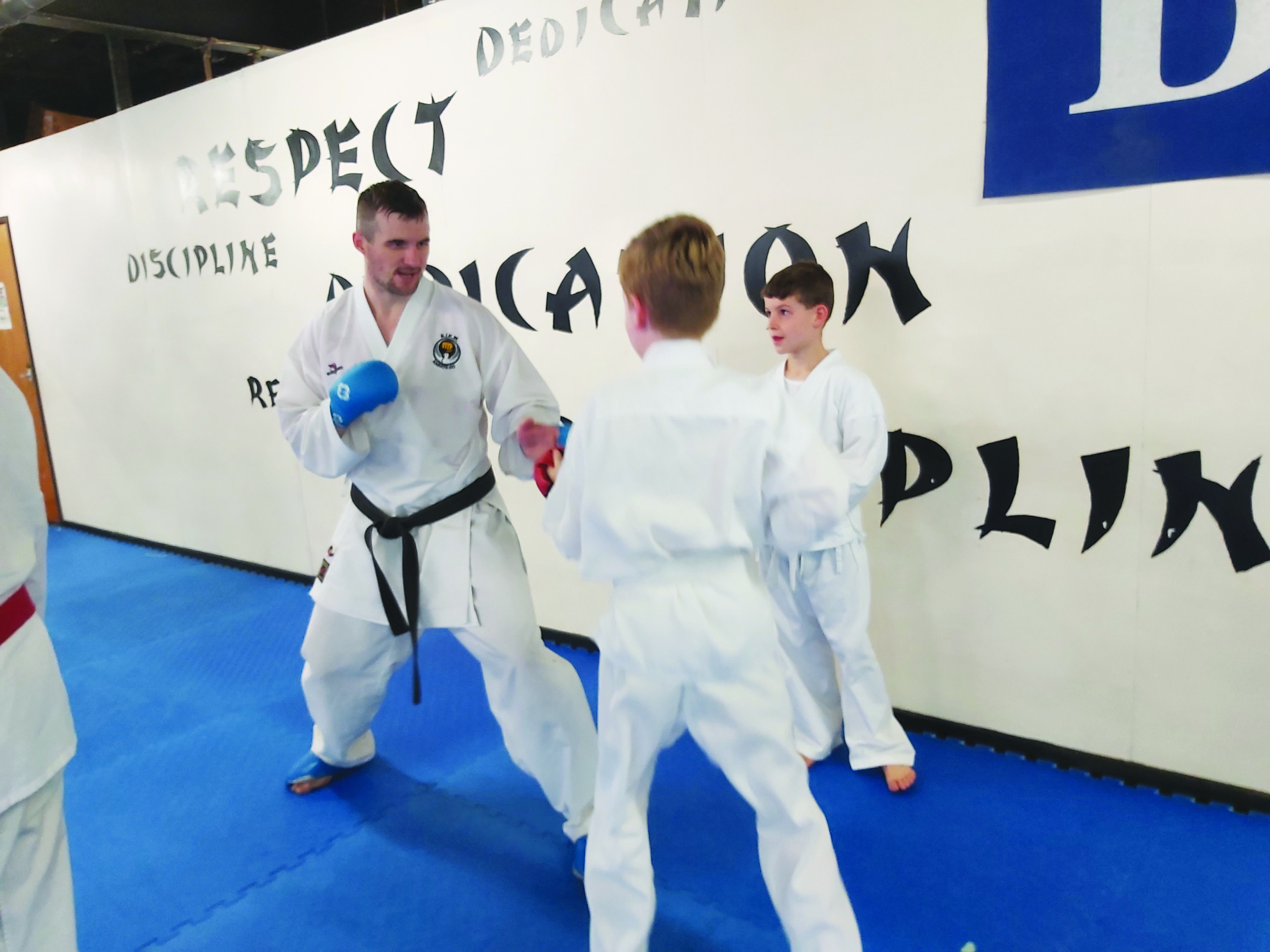 Karate international James Brunton demonstrates fighting techniques to young students