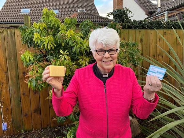 MESSAGE: Rev Dr Liz Hughes holds her Covid-19 vaccination card and a bar of soap