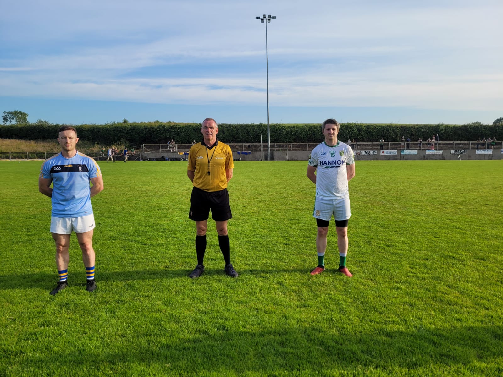 Rossa captain Ciaran Orchin and Aghagallon skipper Darryl McAlernon are pictured with referee Fionntán McCotter before Wednesday night\'s game at Páirc Na nGael  