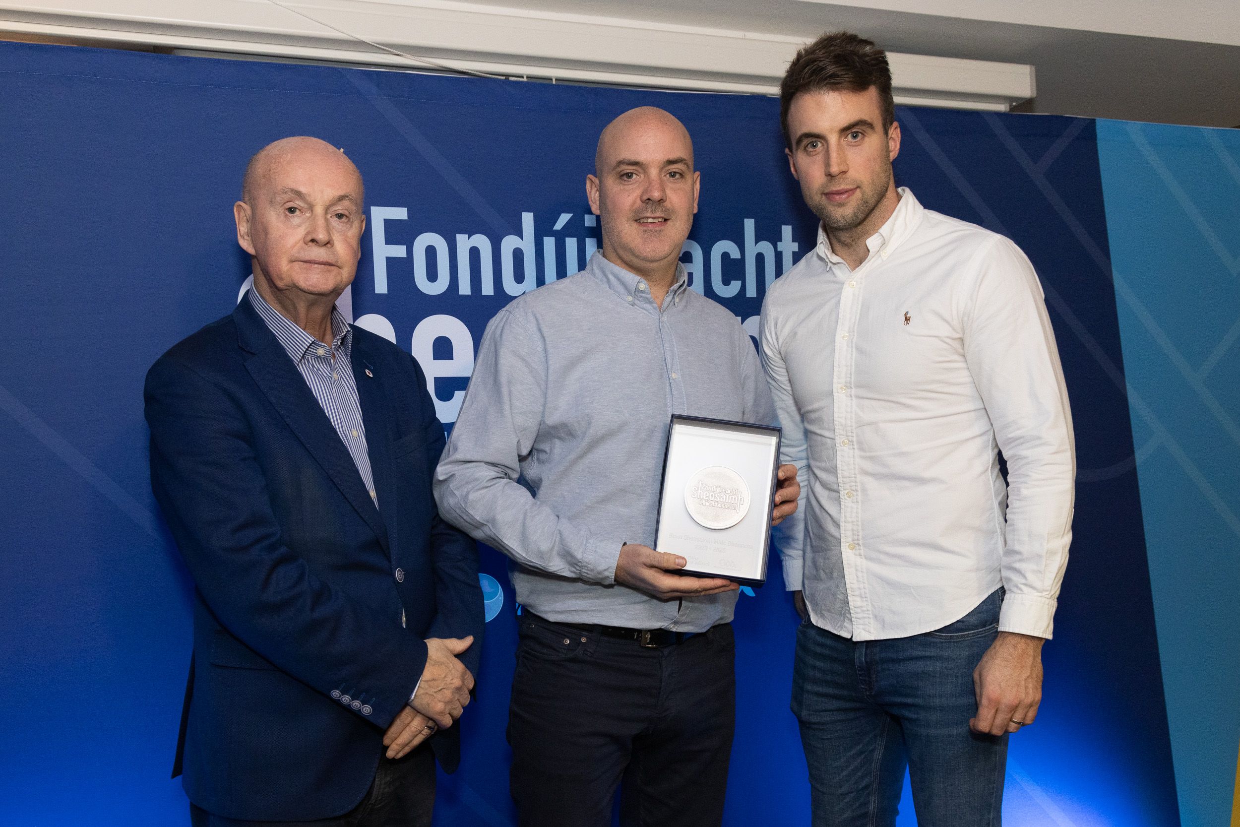 AWARDS: Pat Carey (Glór na nGael Chairman) and Paul Conroy (GAA Irish language ambassador) presenting a silver medal to Rónán Mac Aoidh, representing Lámh Dhearg