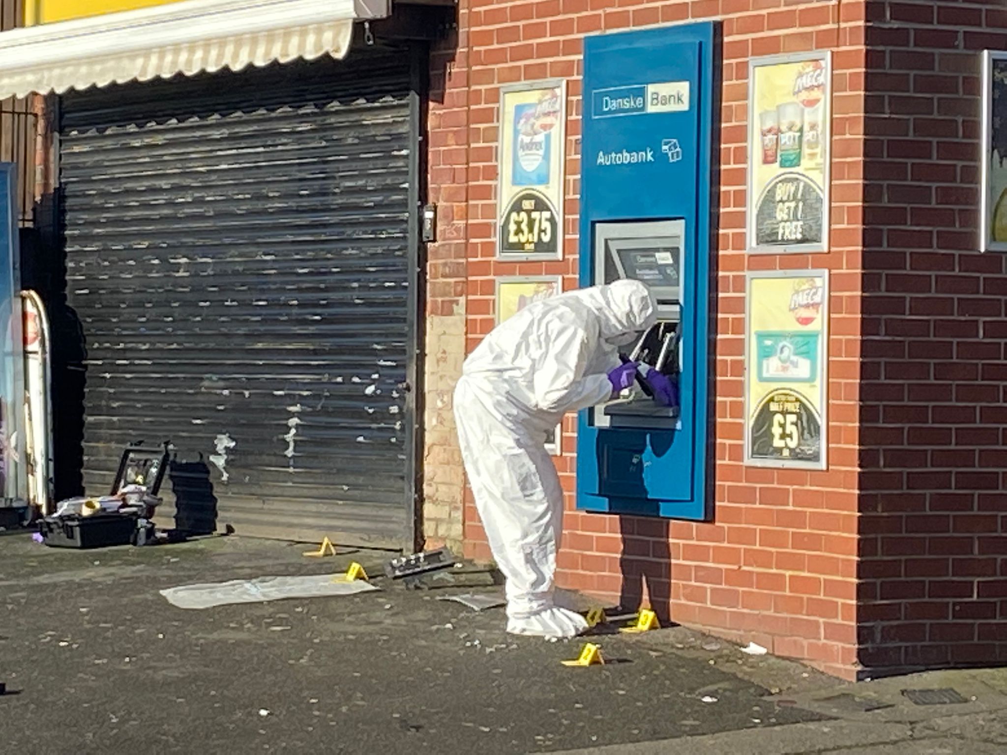 AFTERMATH: A forensics officer at the ATM outside a shop on the Ballysillan Road