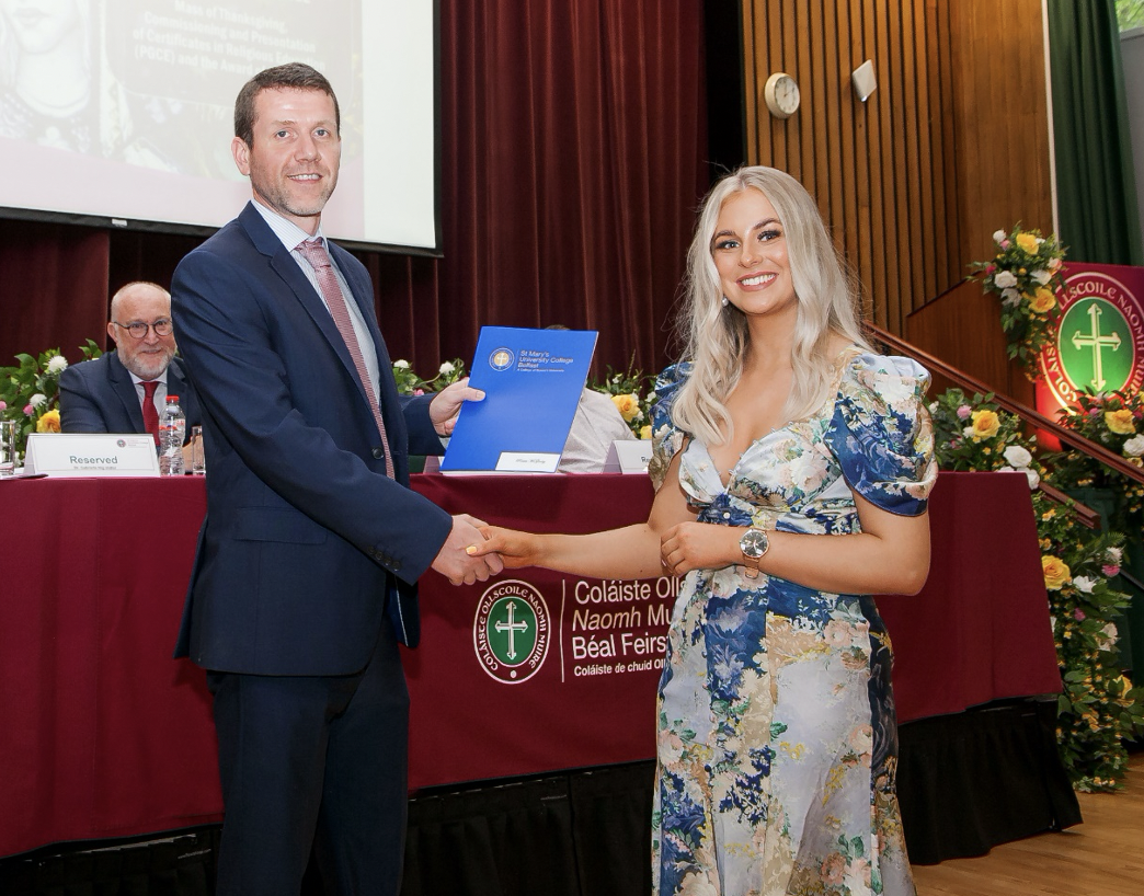 Ciarán Mac Giolla Bhéin, Chief Executive, Comhairle na Gaelscolaíocta, presents Róisín Nic Fhionnghaile with her certificate in Bilingual Education
