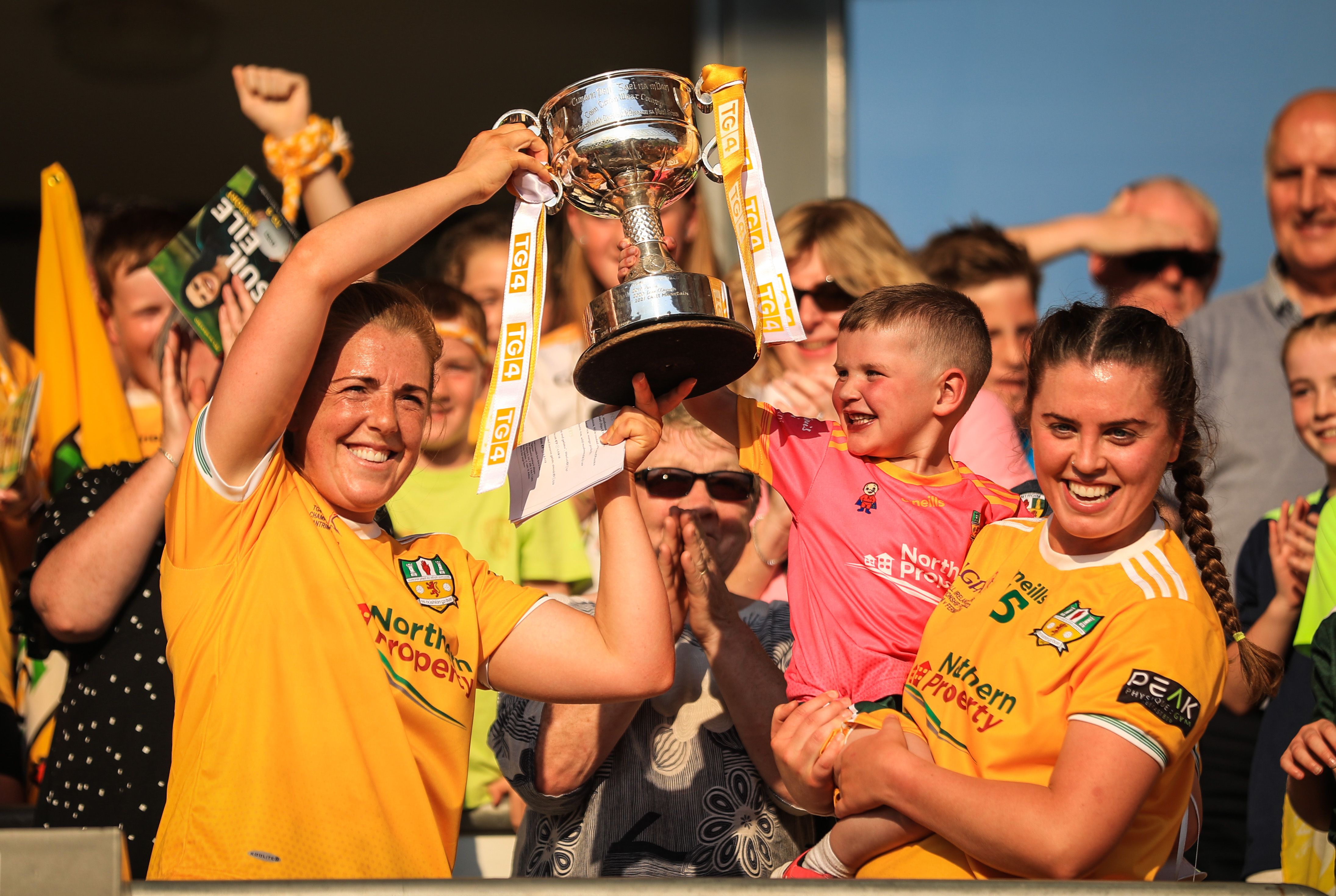 Cathy Carey lifts the West County Hotel Cup with the help of top-scorer Grainne McLaughlin and Dáithí MacGabhann