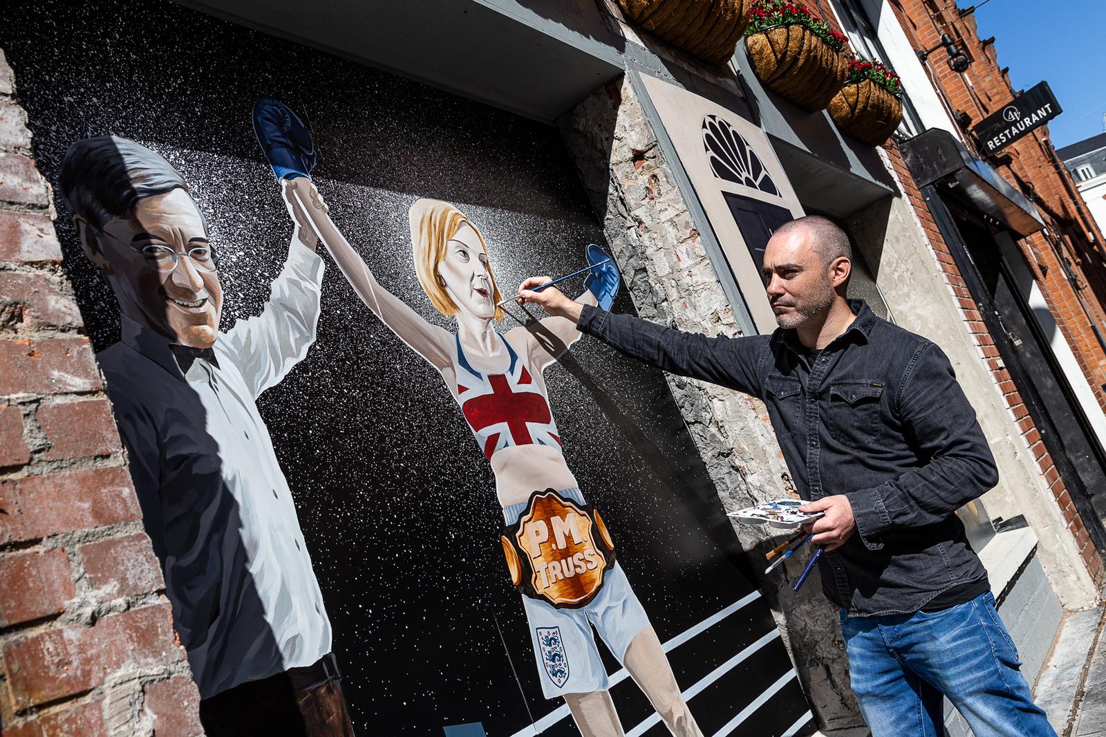 TRUSS ISSUES: Artist Ciaran Gallagher puts the final touches to a new mural depicting Liz Truss\' victory in Belfast\'s Cathedral Quarter
