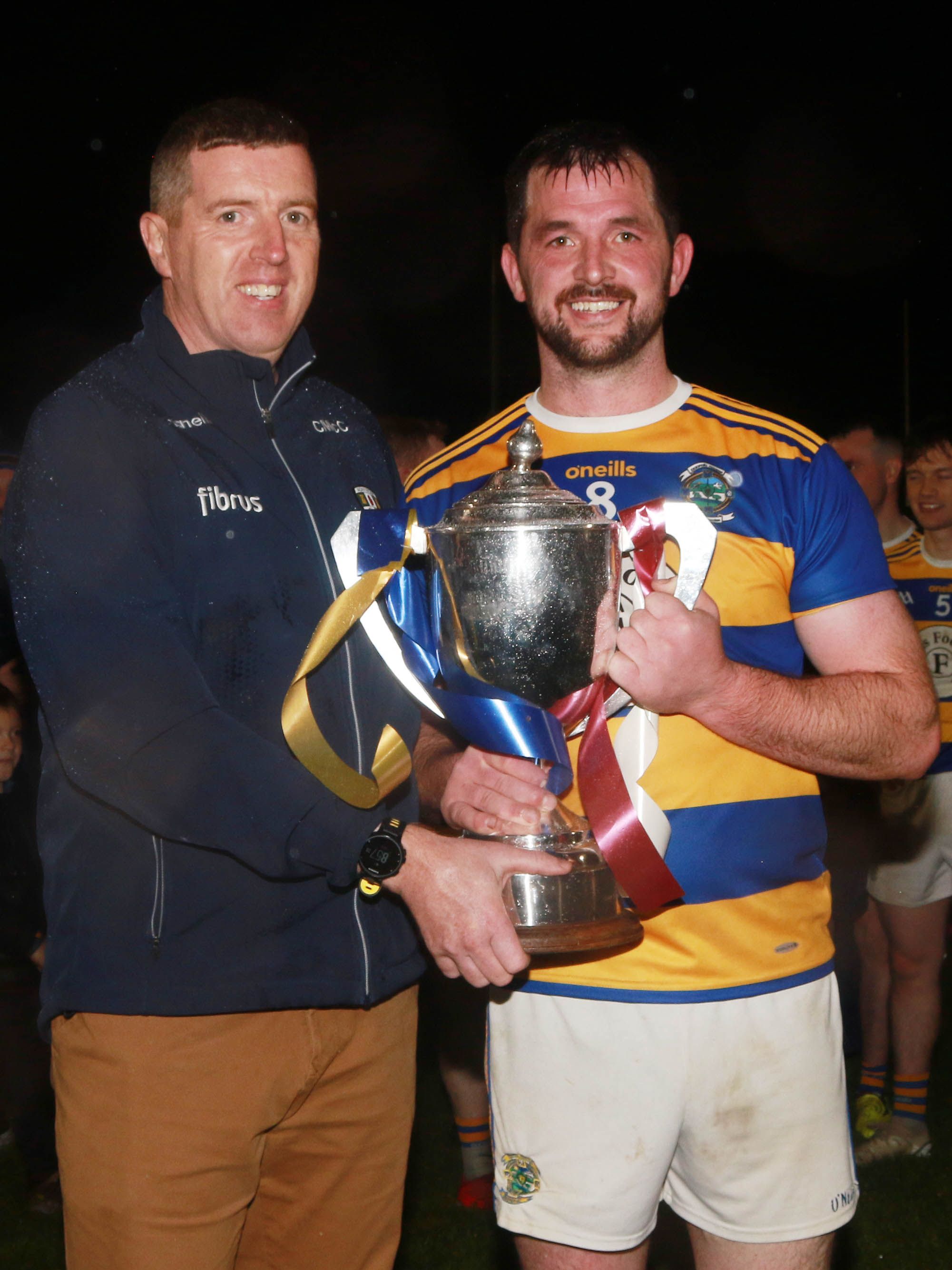 Rasharkin captain Thomas McMullan is presented with the trophy by Antrim chairman, Ciarán McCavana