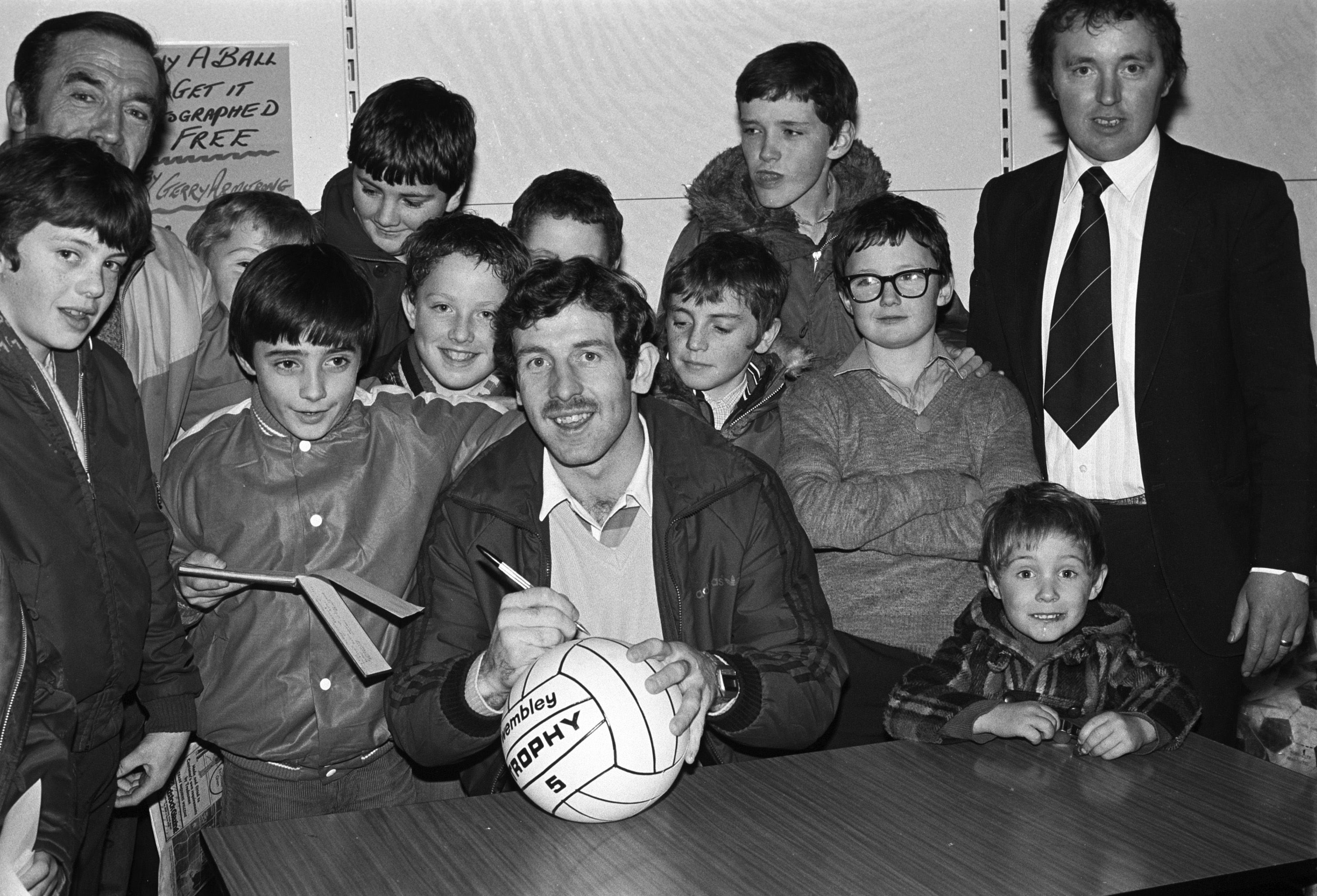 SIGNING ON: Northern Ireland football international Gerry Armstrong signs autographs for young fans at Curley\'s Supermarket