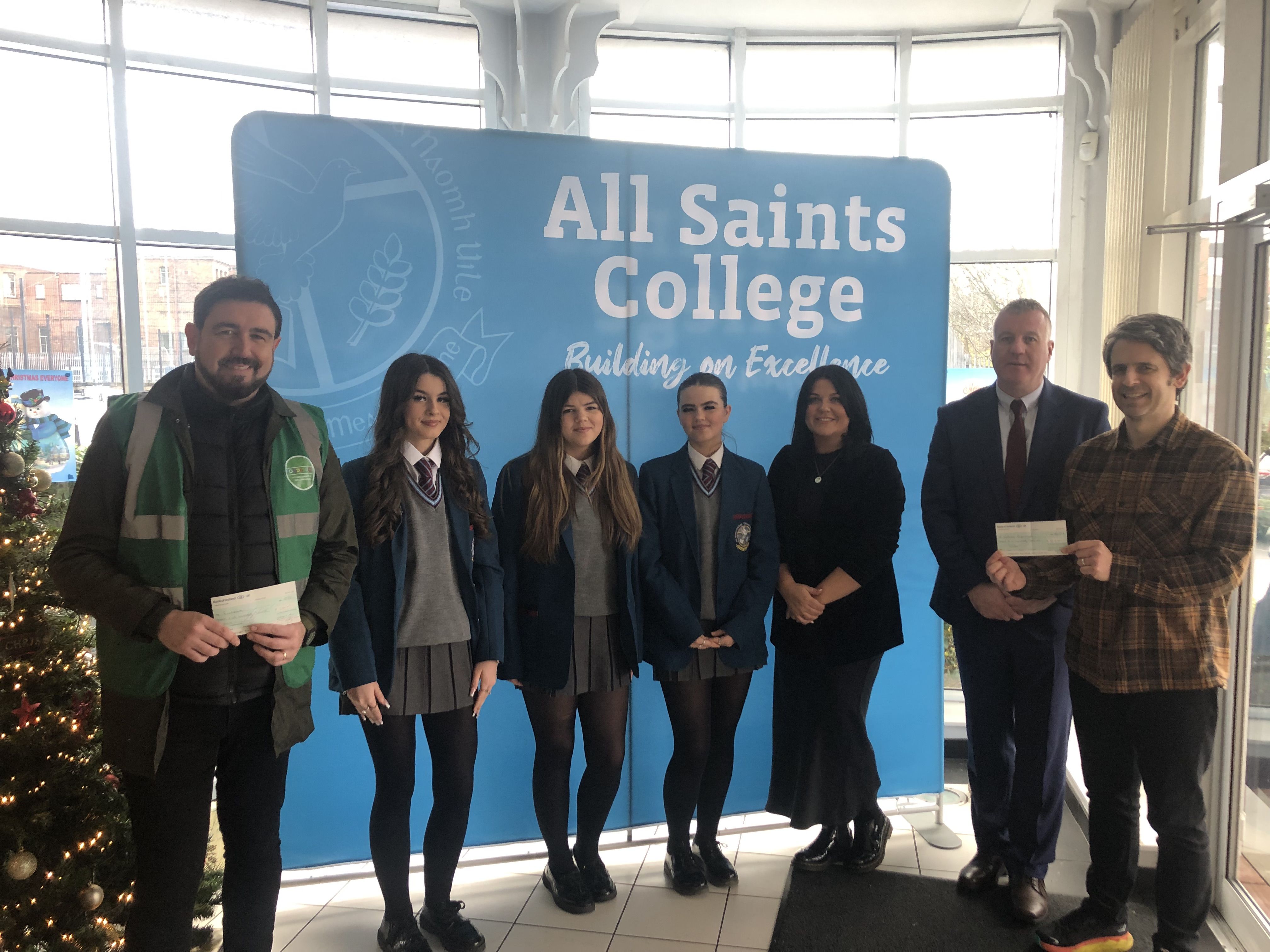 DONATIONS: Paul Doherty of Foodstock, Pupils from All Saints College, teacher Deirdre Vallely, Vice-Principal Damien Coyle and Kieran Hughes from the Welcome Organisation