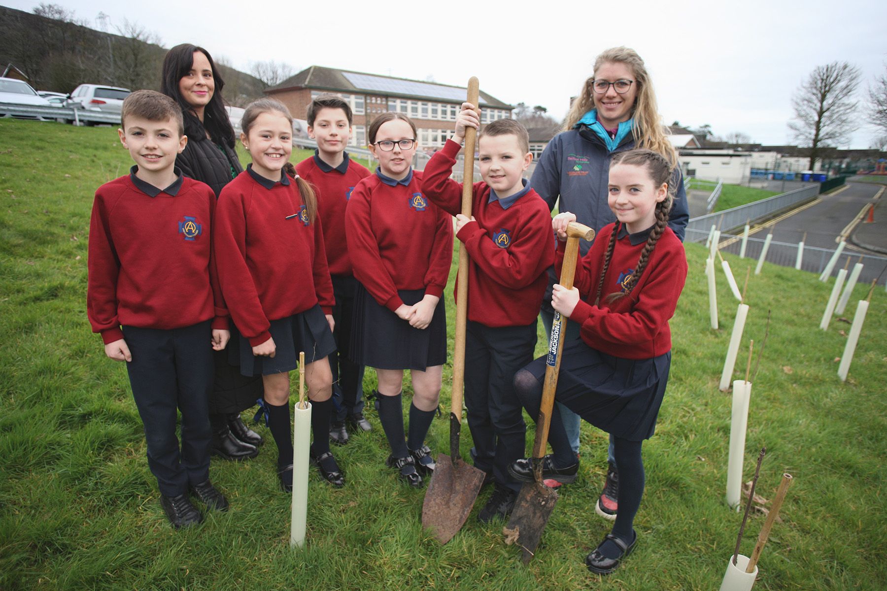 MANY HANDS: Teacher Rachel McPolin and Lisa Critchley from Belfast Hills help pupils plant saplings in St Oliver Plunkett Primary School in Lenadoon