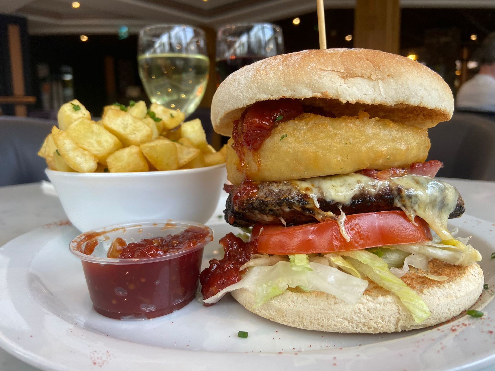 Loaded 6oz Beef Burger, rested on a floury bap with lettuce and tomato and topped with melted cheese, maple bacon, onion rings and relish. 