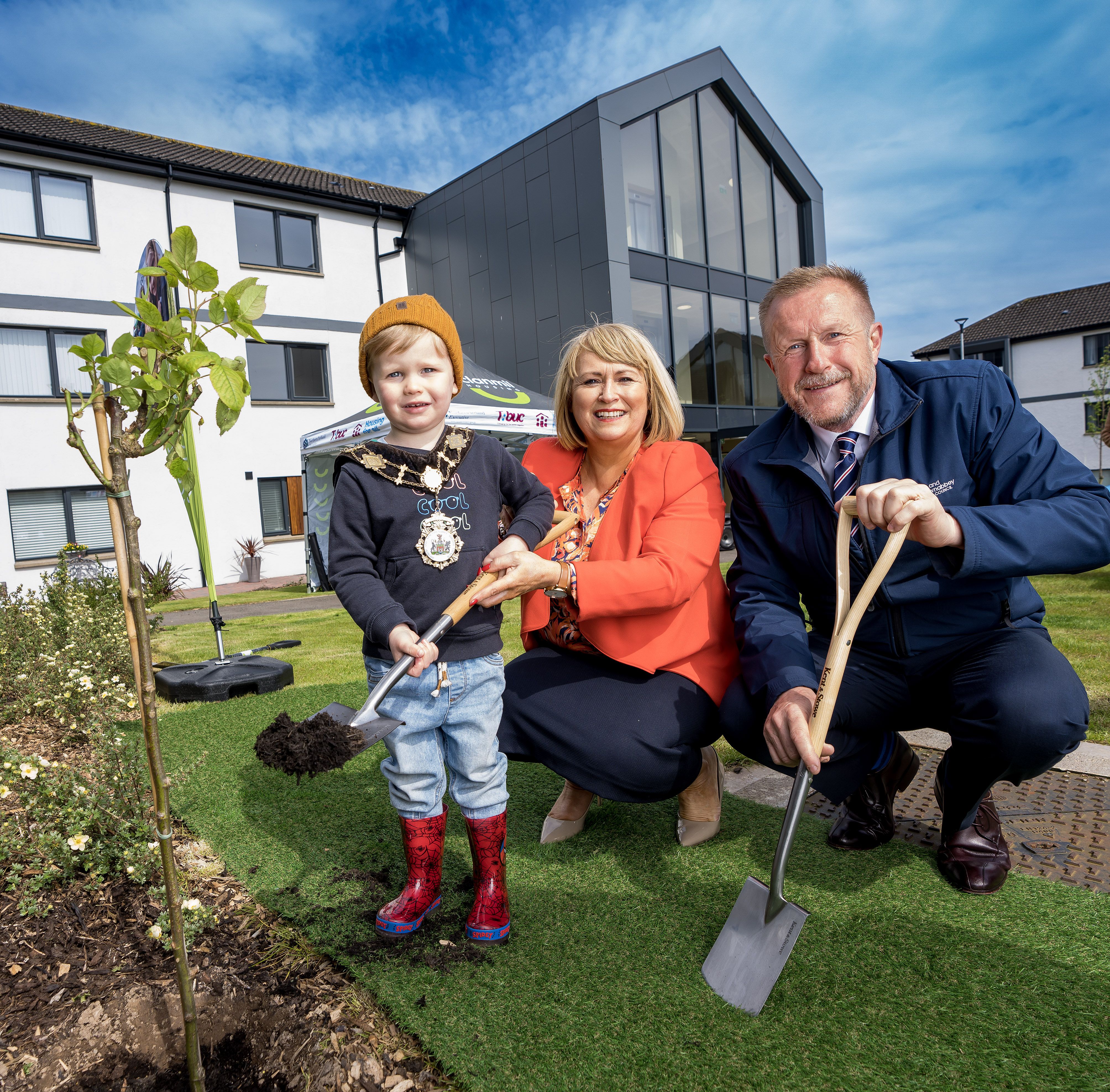WELCOME: Mayor of Antrim and Newtownabbey Alderman Stephen Ross with Clanmil Group Chief Executive Carol McTaggart and Noah Mulvenna planting a rose bush at the official opening of Glendun Court and Glenwherry Court