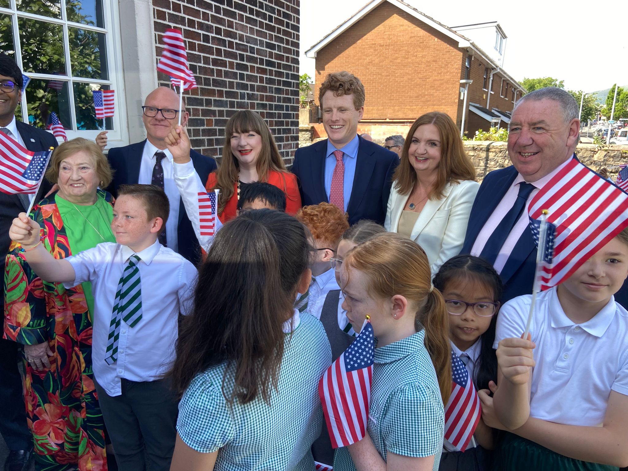 FÁITLE: Paul Maskey MP, Belfast Deputy Lord Mayor, Councillor Áine Groogan, US Special Envoy Joe Kennedy III, Head of NICS Jayne Brady and Gerry McConville, Falls Community Council with students from St Joseph\'s Primary School 