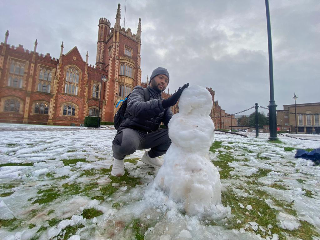 SNOW: Finance student Adarsh Choudhury builds a snowman for the first time outside Queen\'s University on Tuesday
