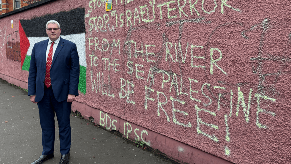 DISAPPROVAL: Gavin Robinson MP had to cross the city to the Falls to find an offensive message on a wall, such is the progress that\'s been made in East Belfast