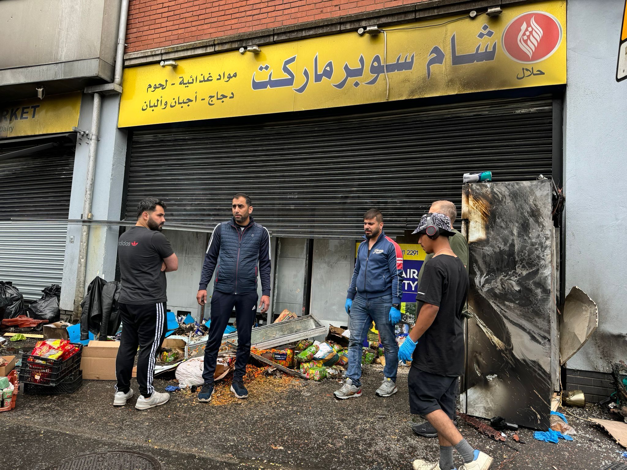 COUNTING THE COST: Muslim shop staff in the ruins of their workplace