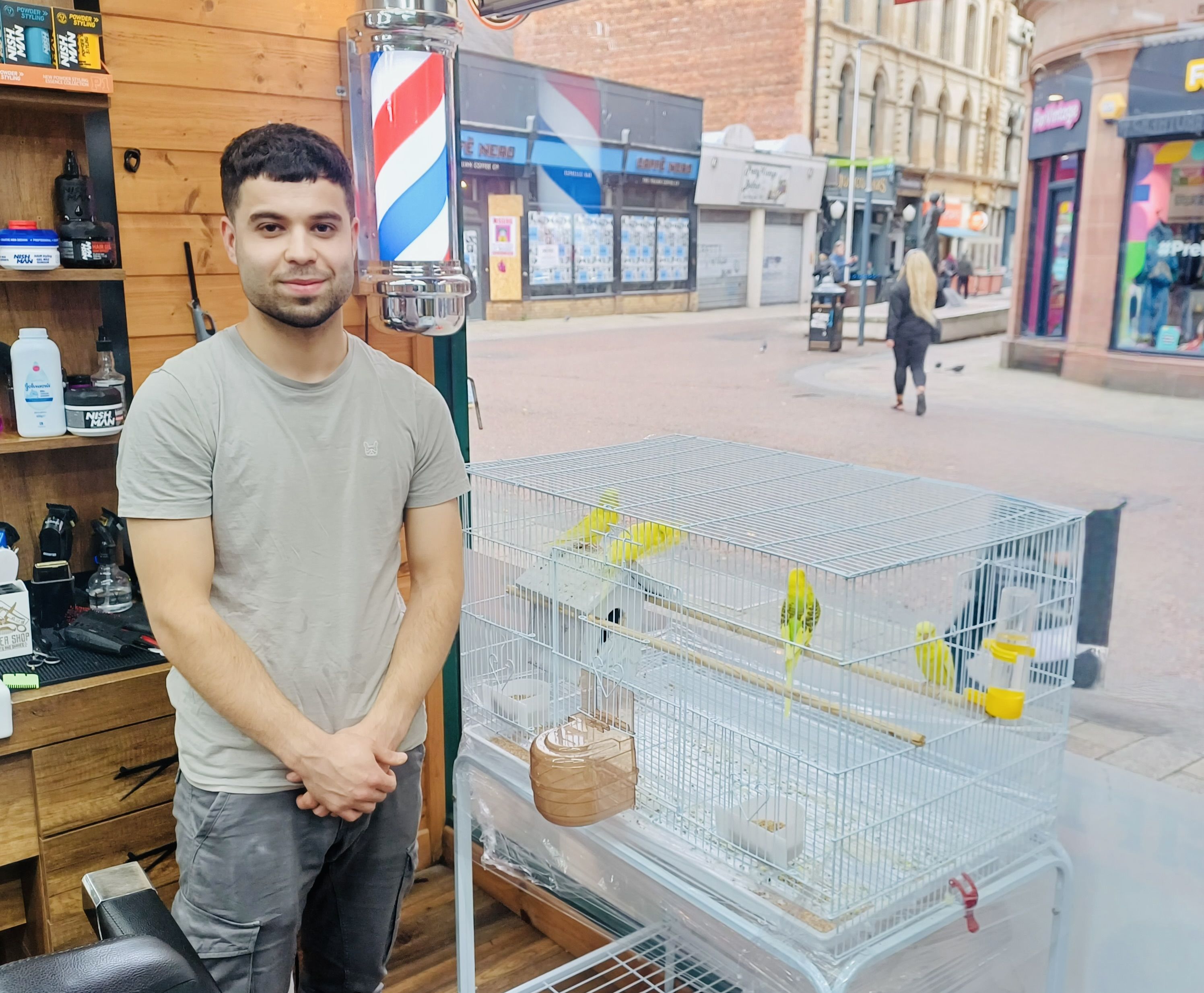 GOOD COMPANY: Ahmed Ali with the budgies in his barber shop in Belfast city centre