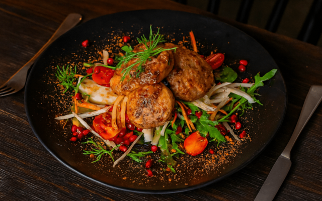 PLATING UP: Sliced pork fillet on a rocket salad with pomegranate and red pepper