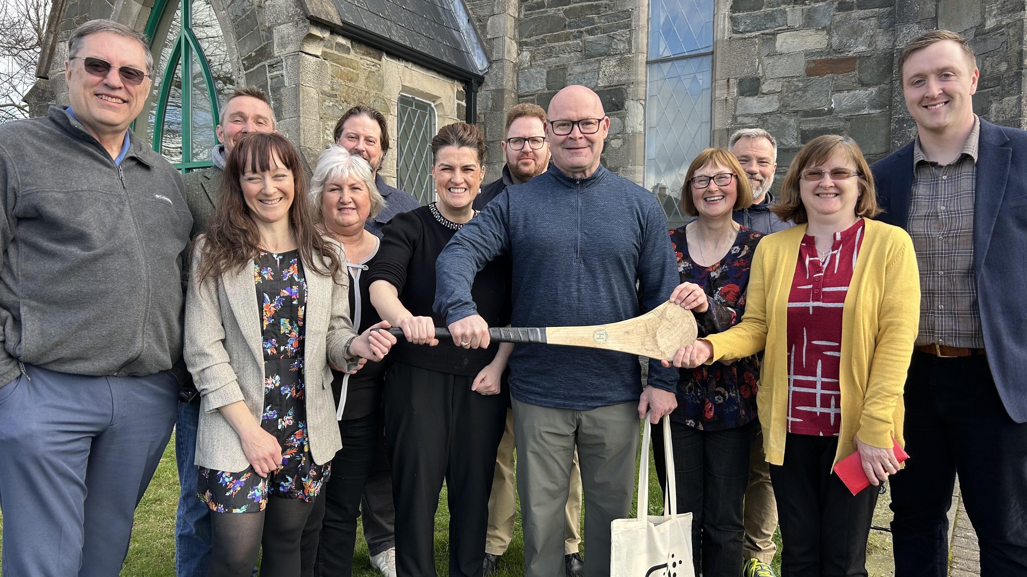 GAME ON! Teamsters President Sean O\'Brien is joined by members of his delegation to received the gift of a camán — a hurley stick — from staff of Buncrana library, Co. Donegal