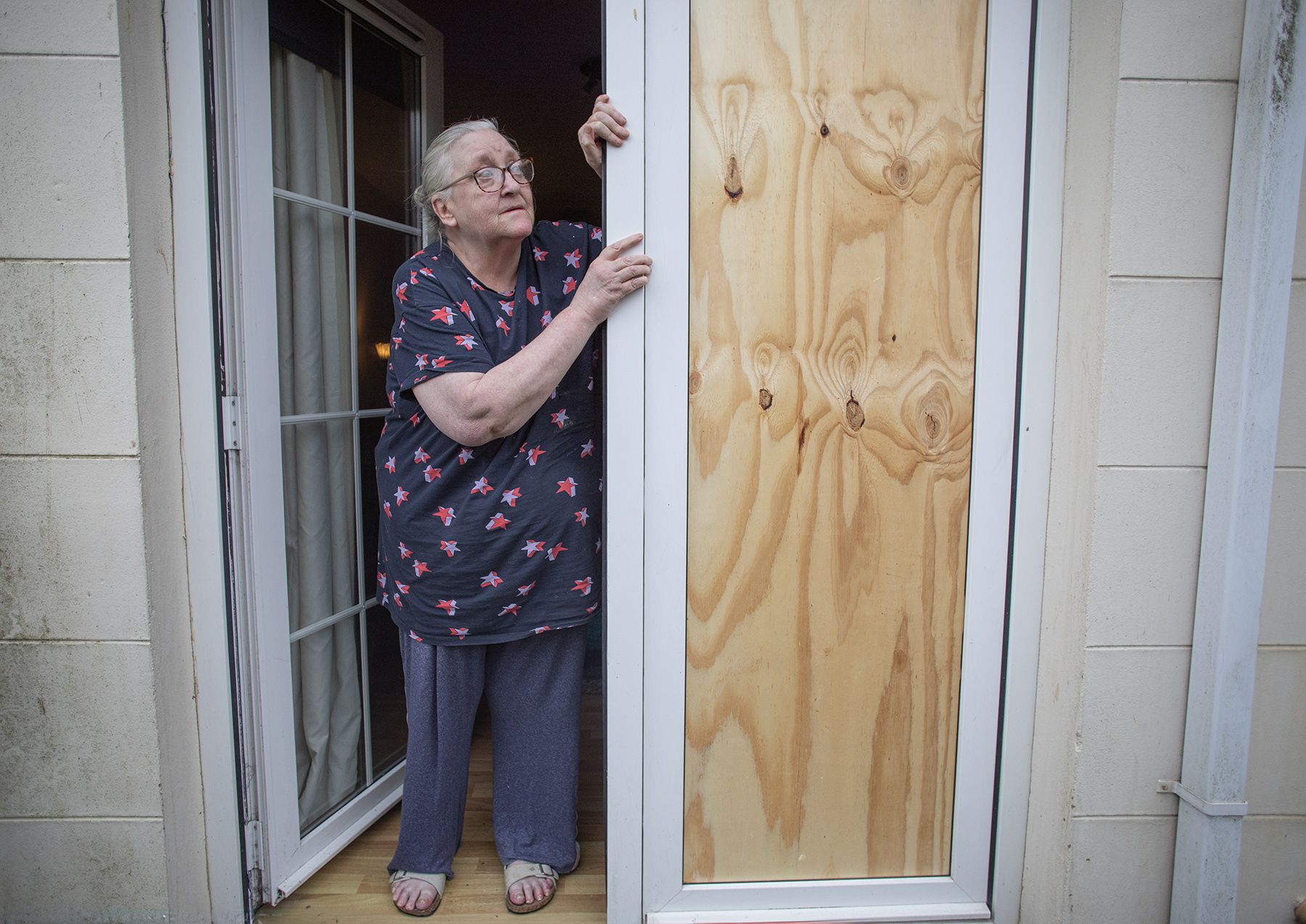 ATTACK: Elizabeth McCloskey looks at the broken window of her apartment on the Suffolk Road