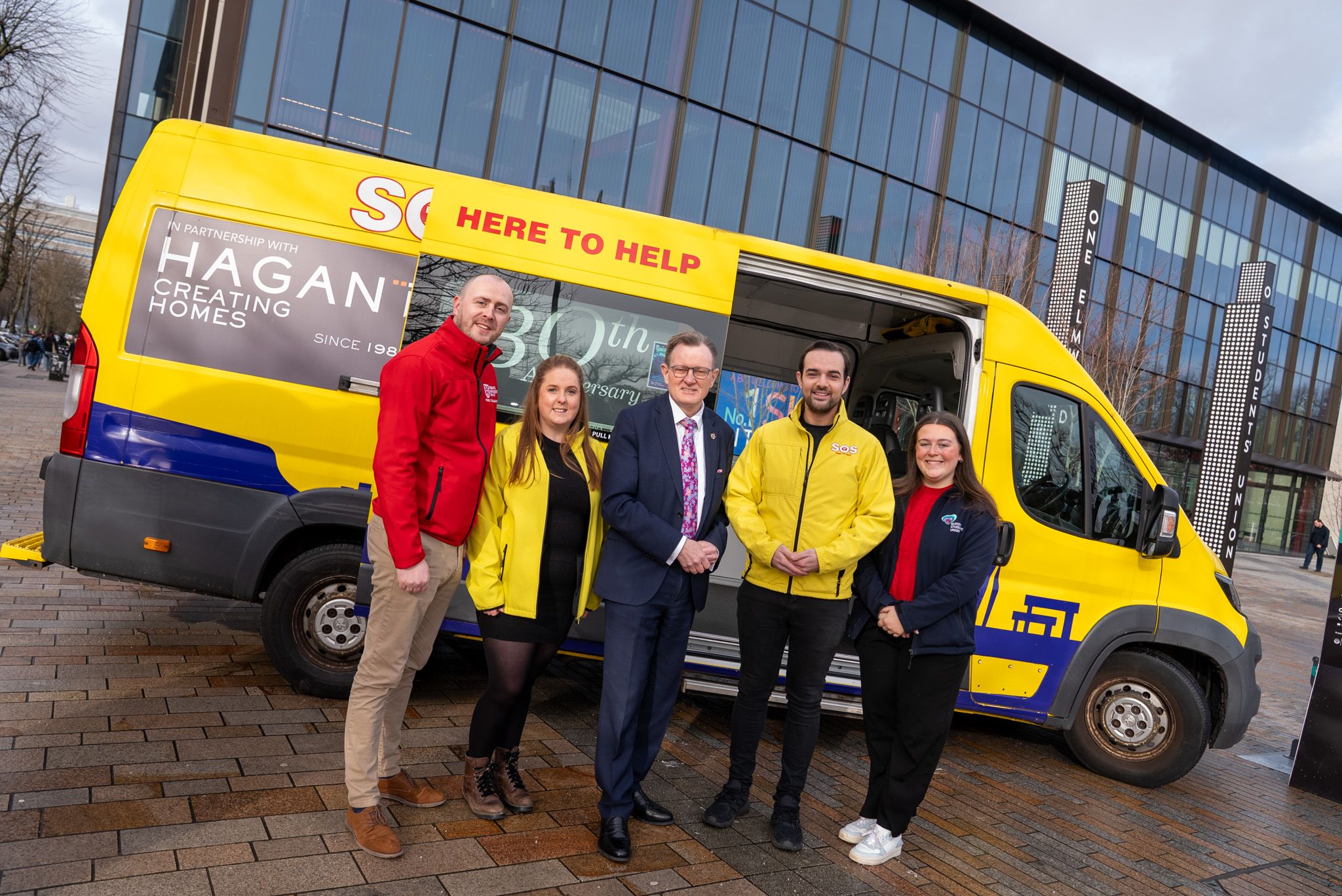 Ryan Rankin (Queen\'s Neighbourhood Engagement Officer), Caitlin McCartney (Operations & Stakeholder Manager, SOS Bus NI), Professor Ian Greer (Queen\'s Vice-Chancellor). Micky Murray, CEO of SOS Bus NI and Amy Smith (Queen\'s Students\' Union President)