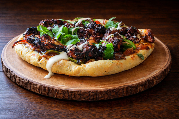 PLATING UP: Chicken tikka pizza with  coriander and mint yoghurt