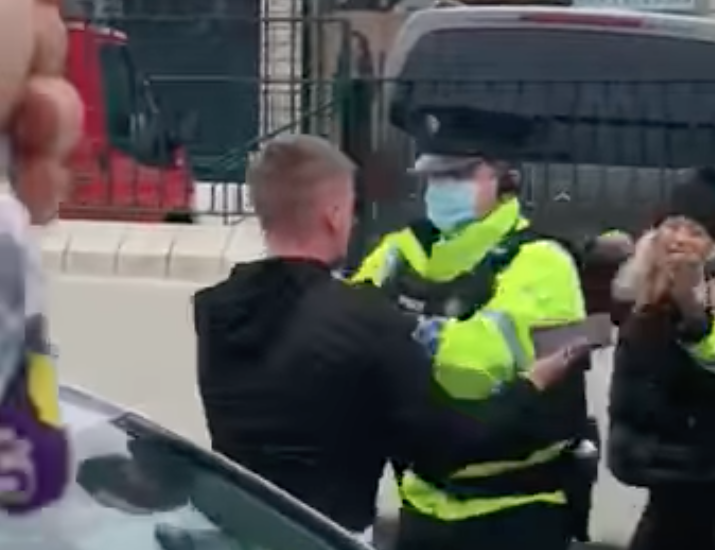 A PSNI officer grapples a mourner on Kennedy Way
