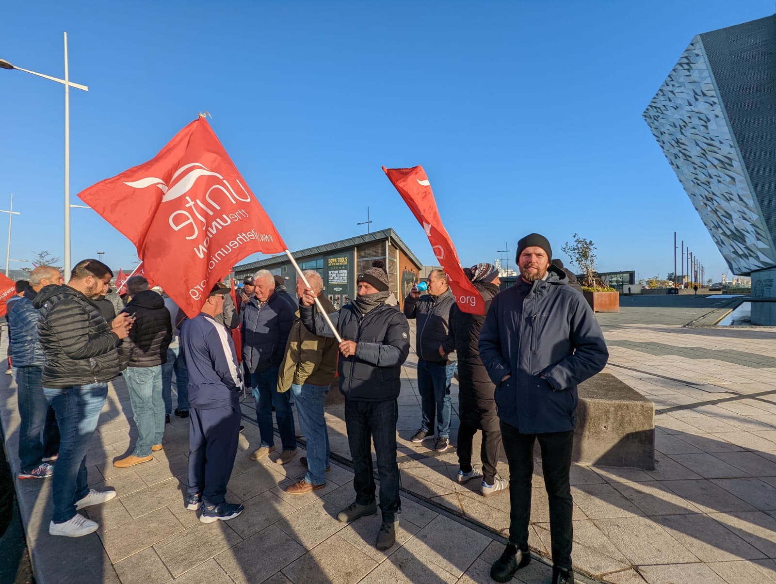 West Belfast MLA Gerry Carroll standing alongside members of Unite union