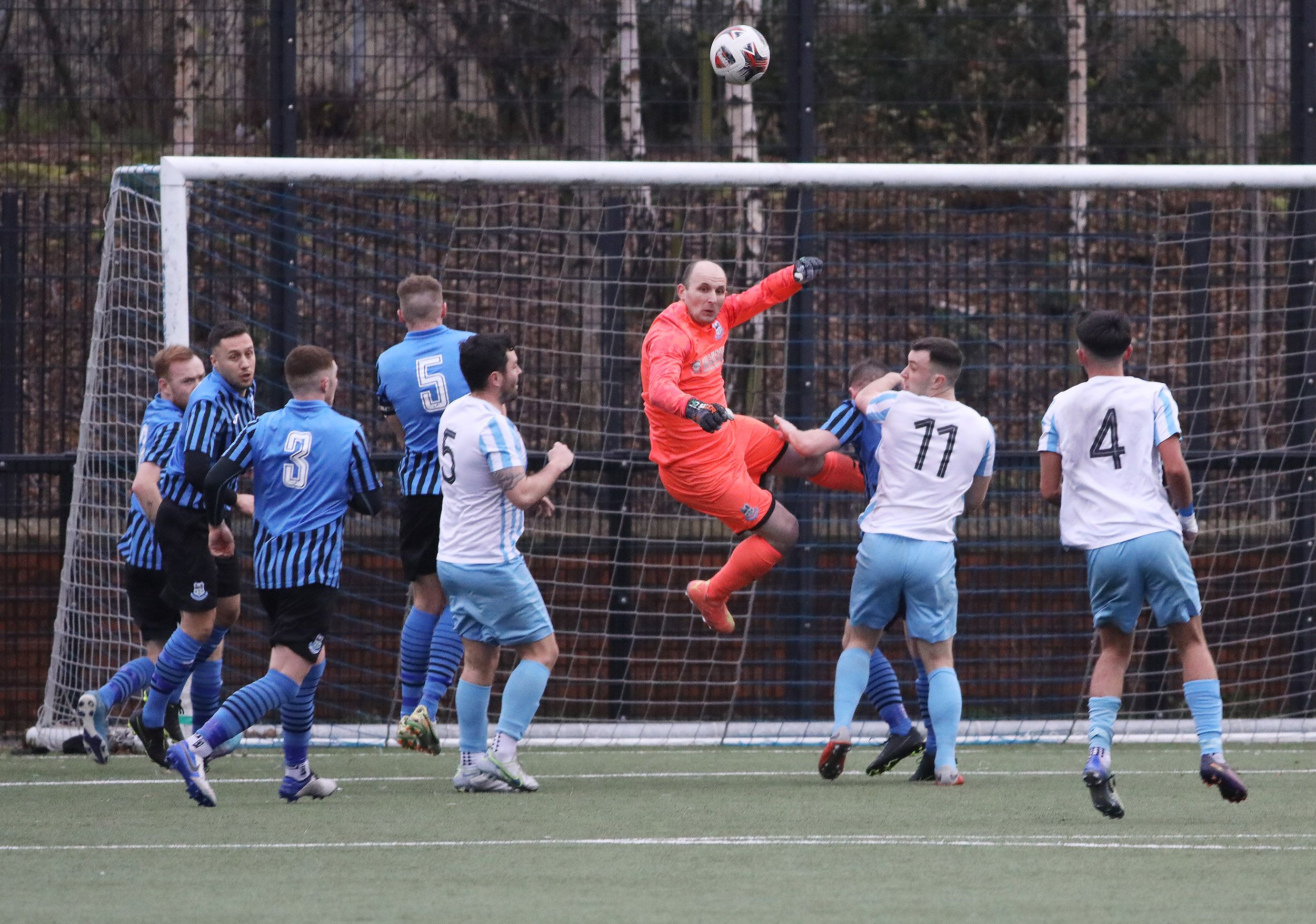 Crumlin United's goalkeeper gets the ball away to safety 