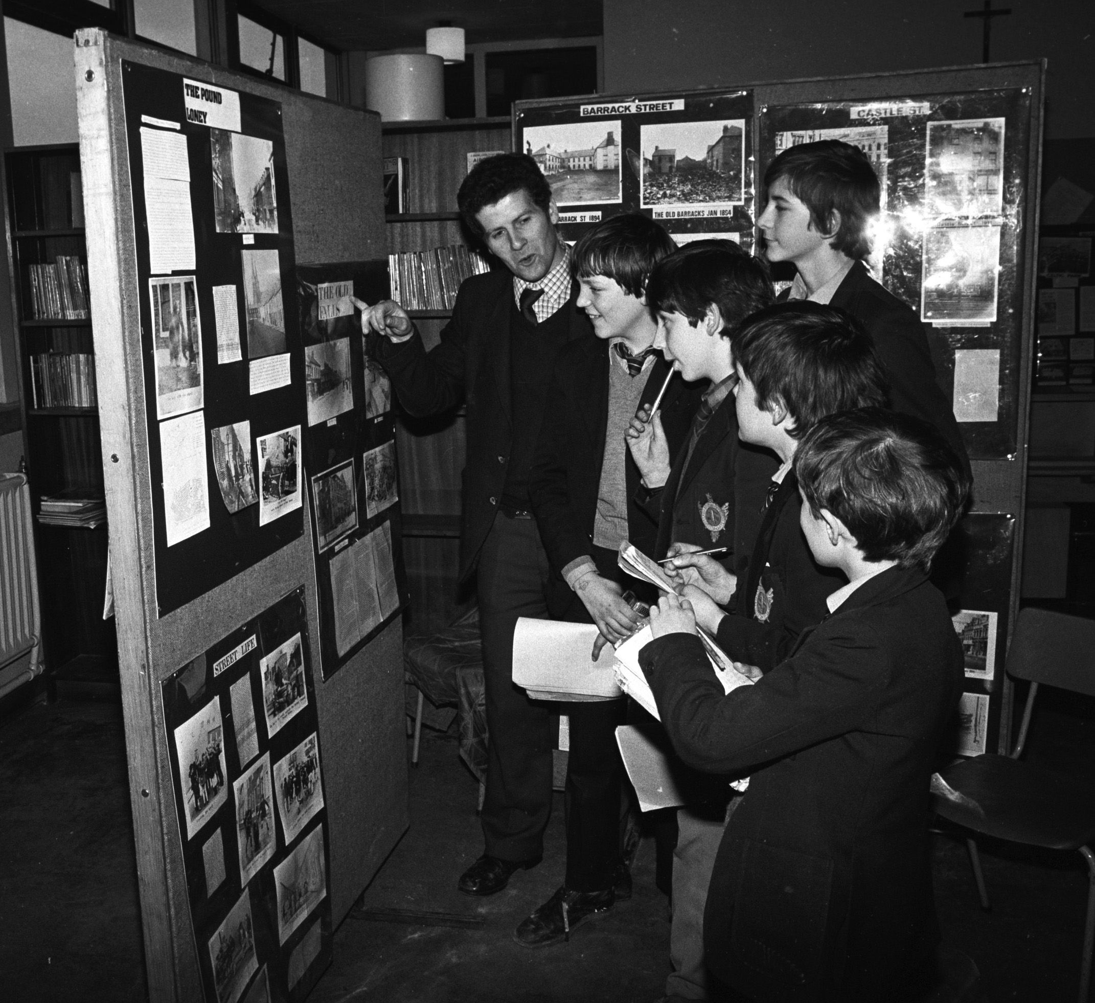 Mr Austin and pupils discuss the Falls Community Council local history display in Beechmount