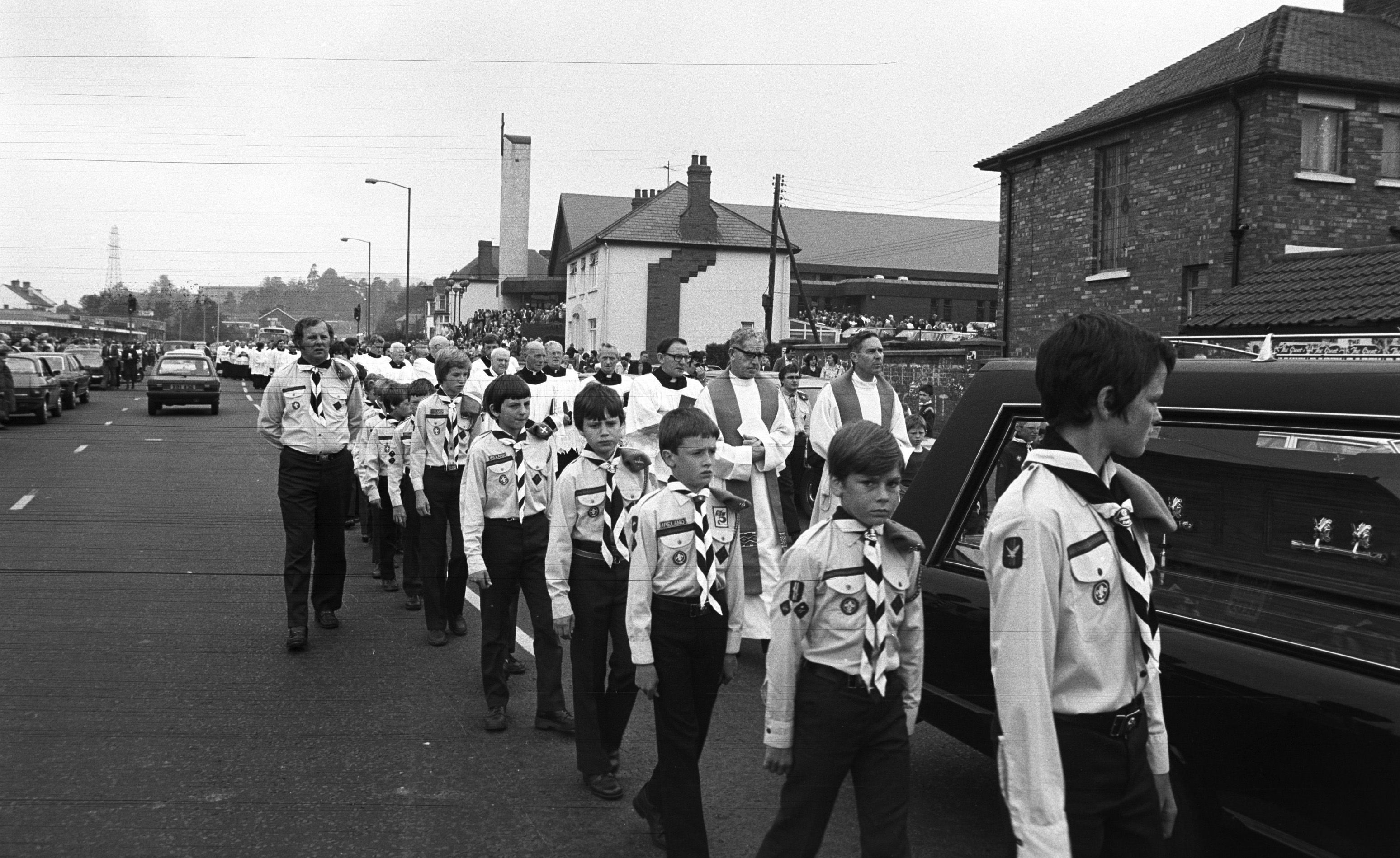 Funeral of Father Denvir, St Agnes' parish priest, with Canons Dallat and Walsh and local scouts and cubs walking alongside the funeral cortege