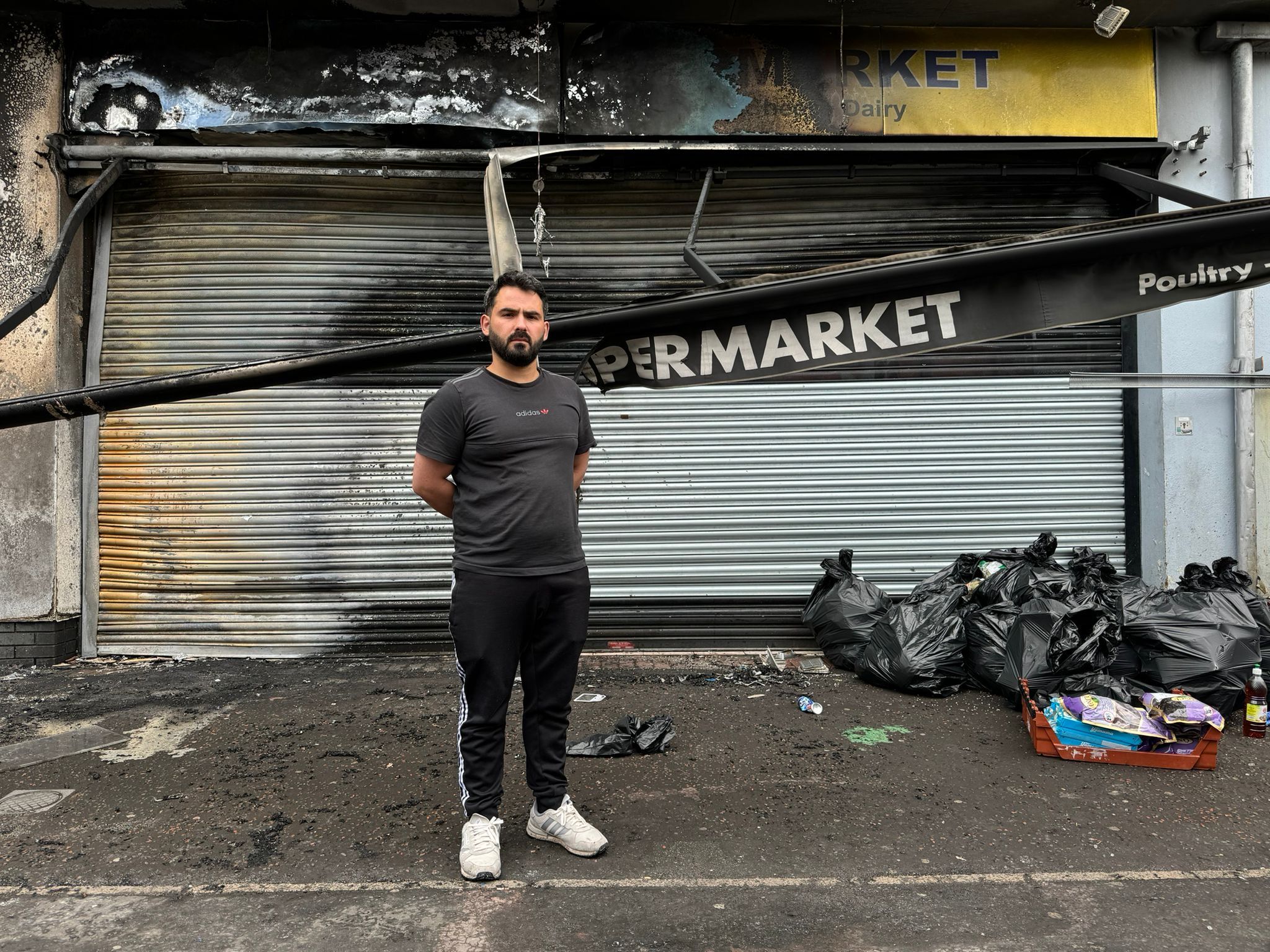 Abdelkader Al Alloush outside his shop which was destroyed during the disorder