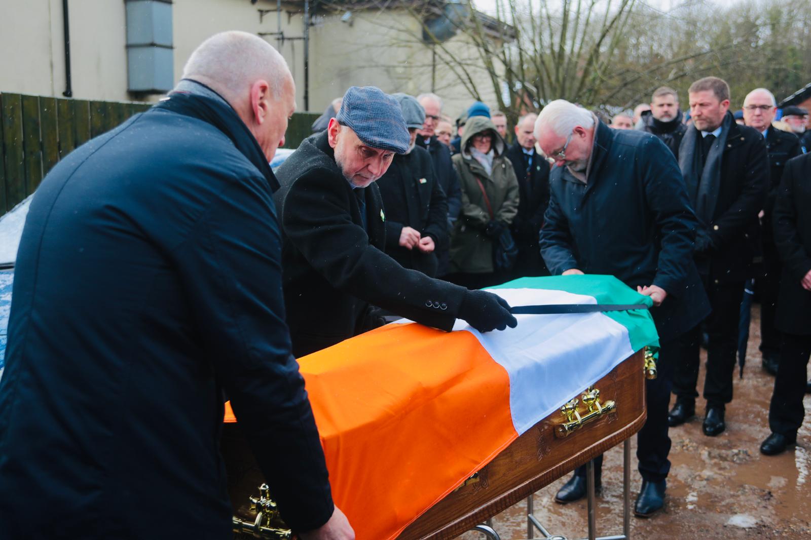 Seán Murray places the tricolour on Ted Howell's coffin