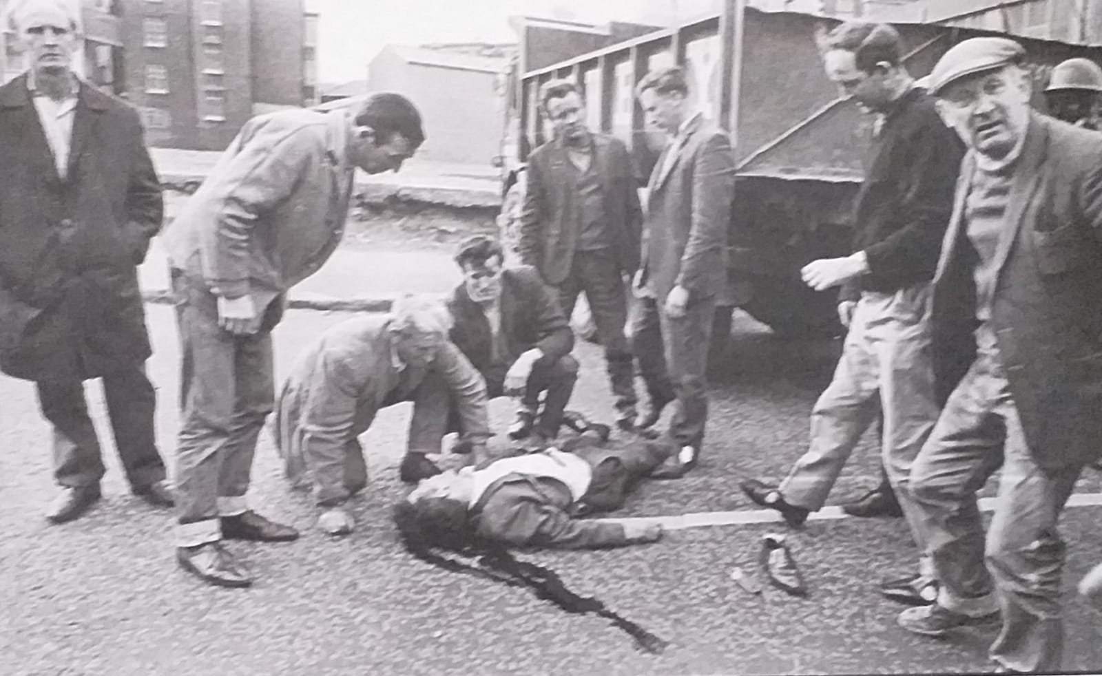 A crowd gathers around Charlie O'Neill after he was run over by a British Army military vehicle