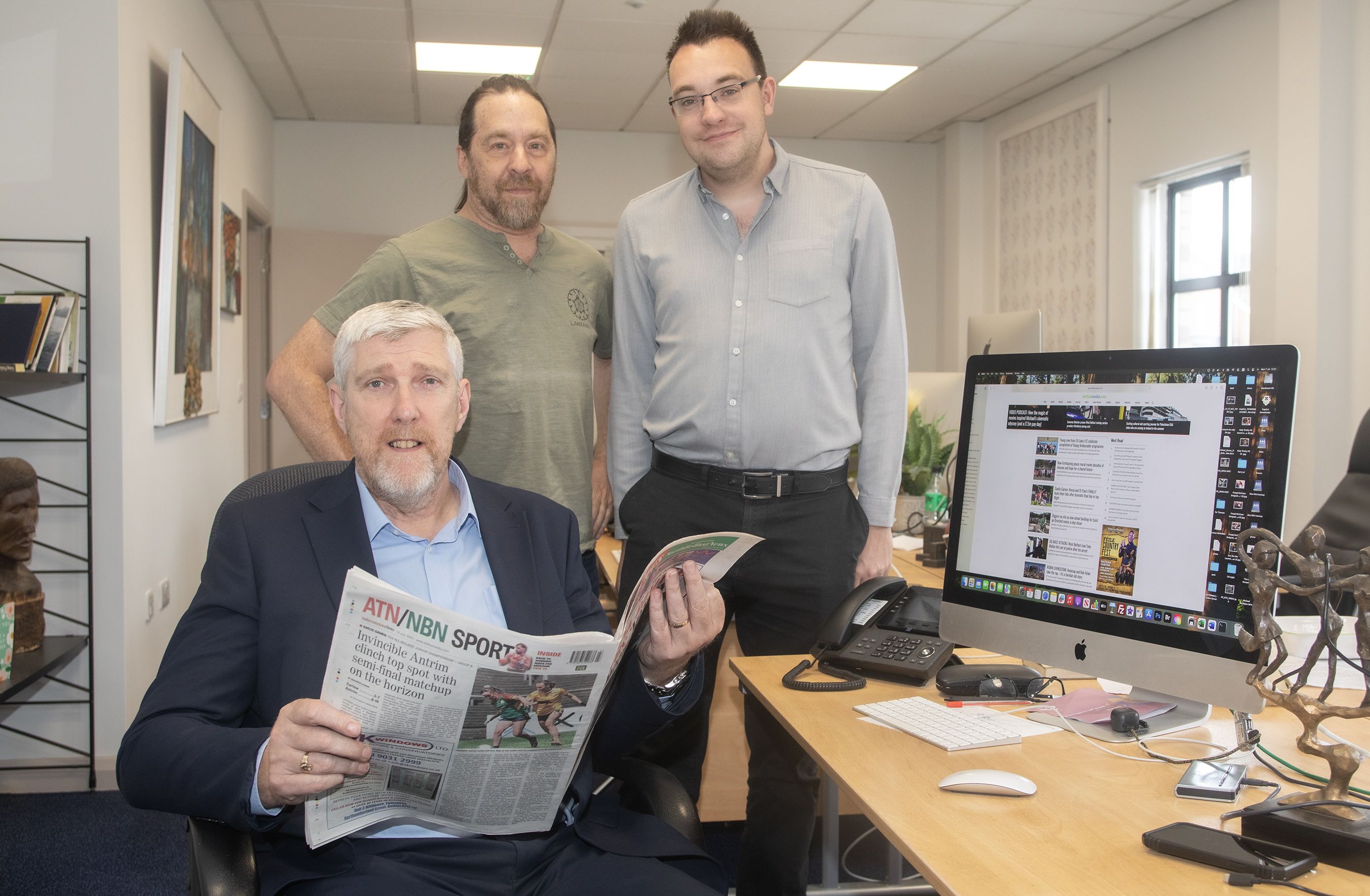 Finance Minister John O'Dowd catches up on the news in the Andersonstown News office with Conor McParland and Scott Silver