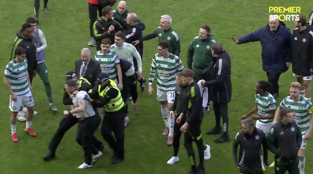 MELÉE: A Rangers fan is led away after a confrontation on the pitch