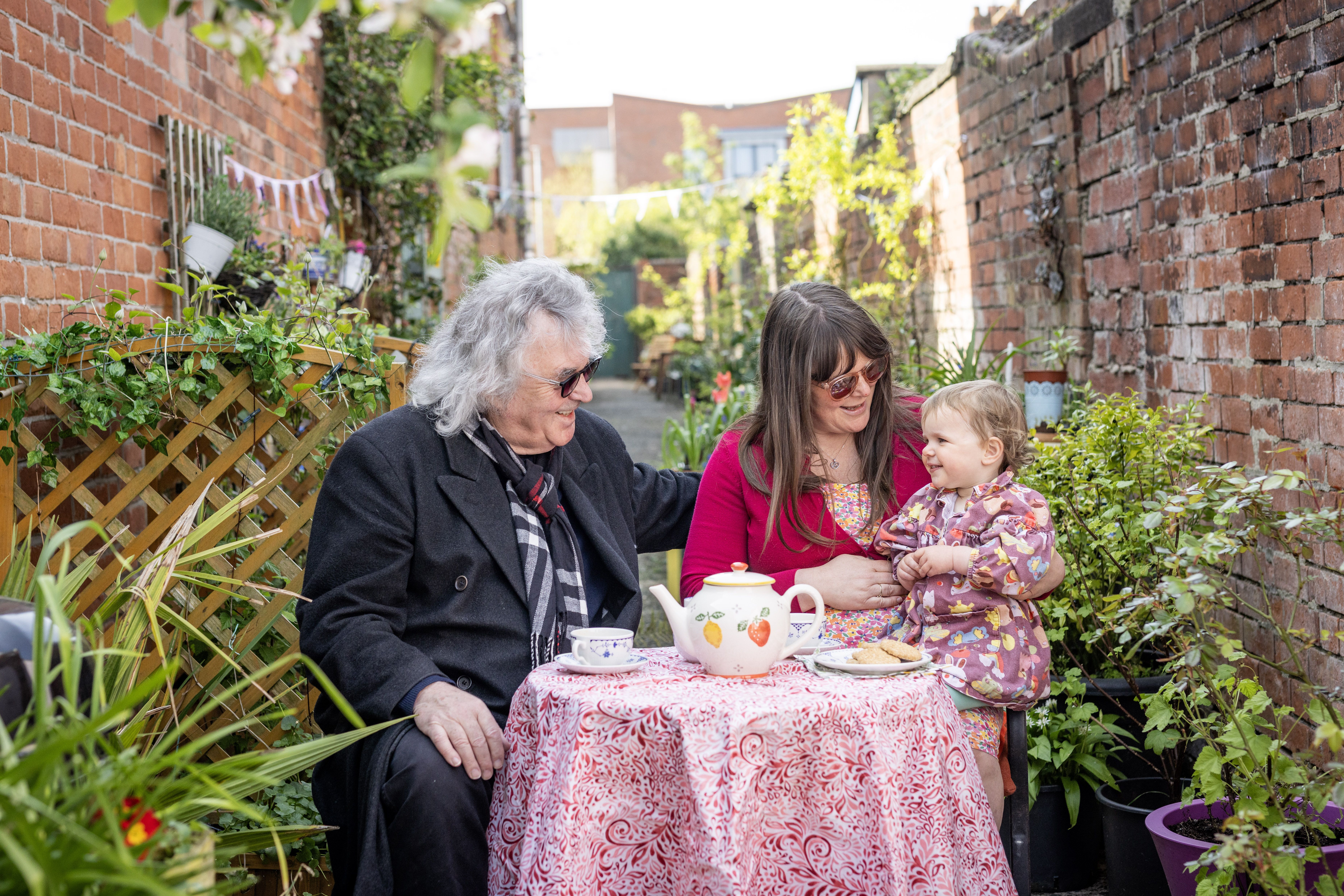 Brendan McCauley and Ruth Patterson and her daughter enjoy the sunshine in their alleyway in South Belfast