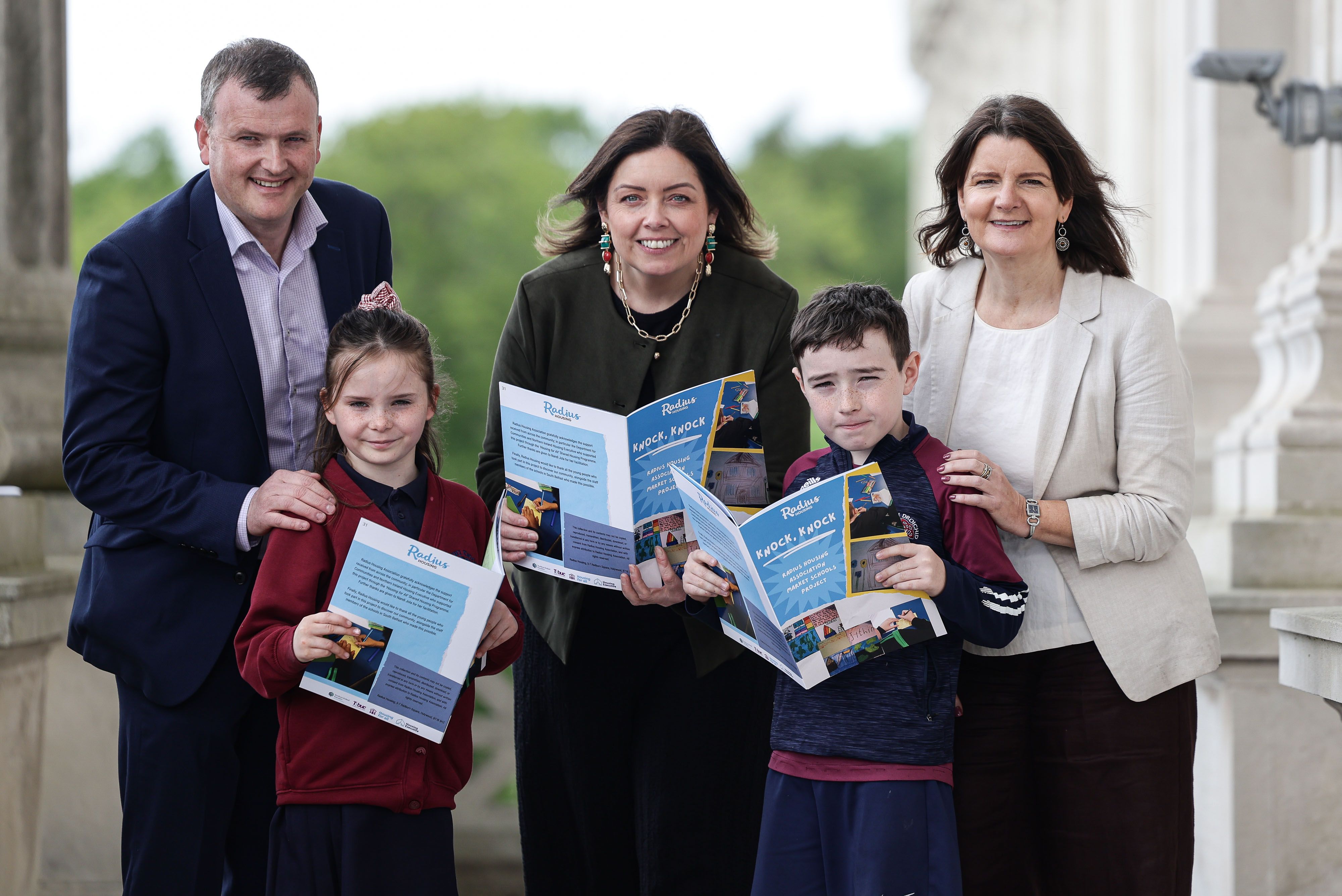 Stephen Reynolds, Housing for All Manager at Northern Ireland Housing Executive; Deirdre Hargey MLA; and Loma Wilson, Director of Communities at Radius Housing, with pupils launching their published ‘Knock Knock’ book