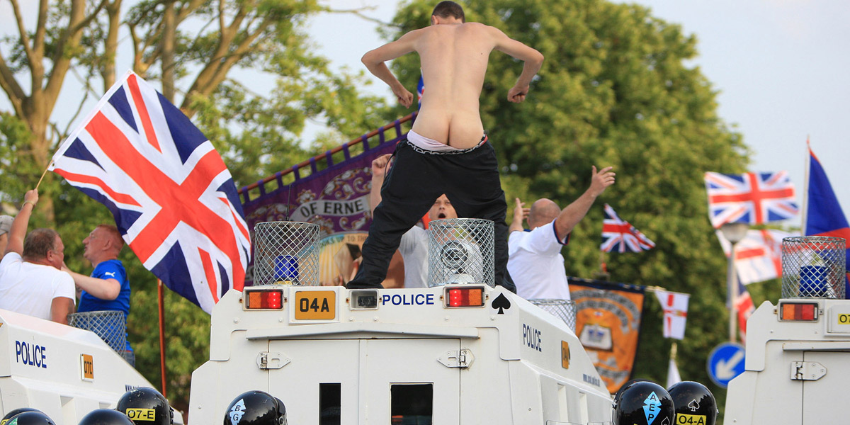 Drunken loyalists atop police Land Rovers as tension builds on the Woodvale Road on the Twelfth night
