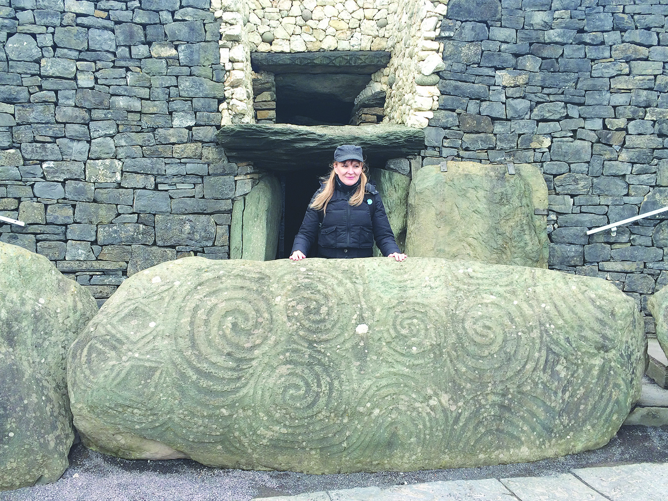 The writer standing behind one of the inscripted stones at the base of the Newgrange mound