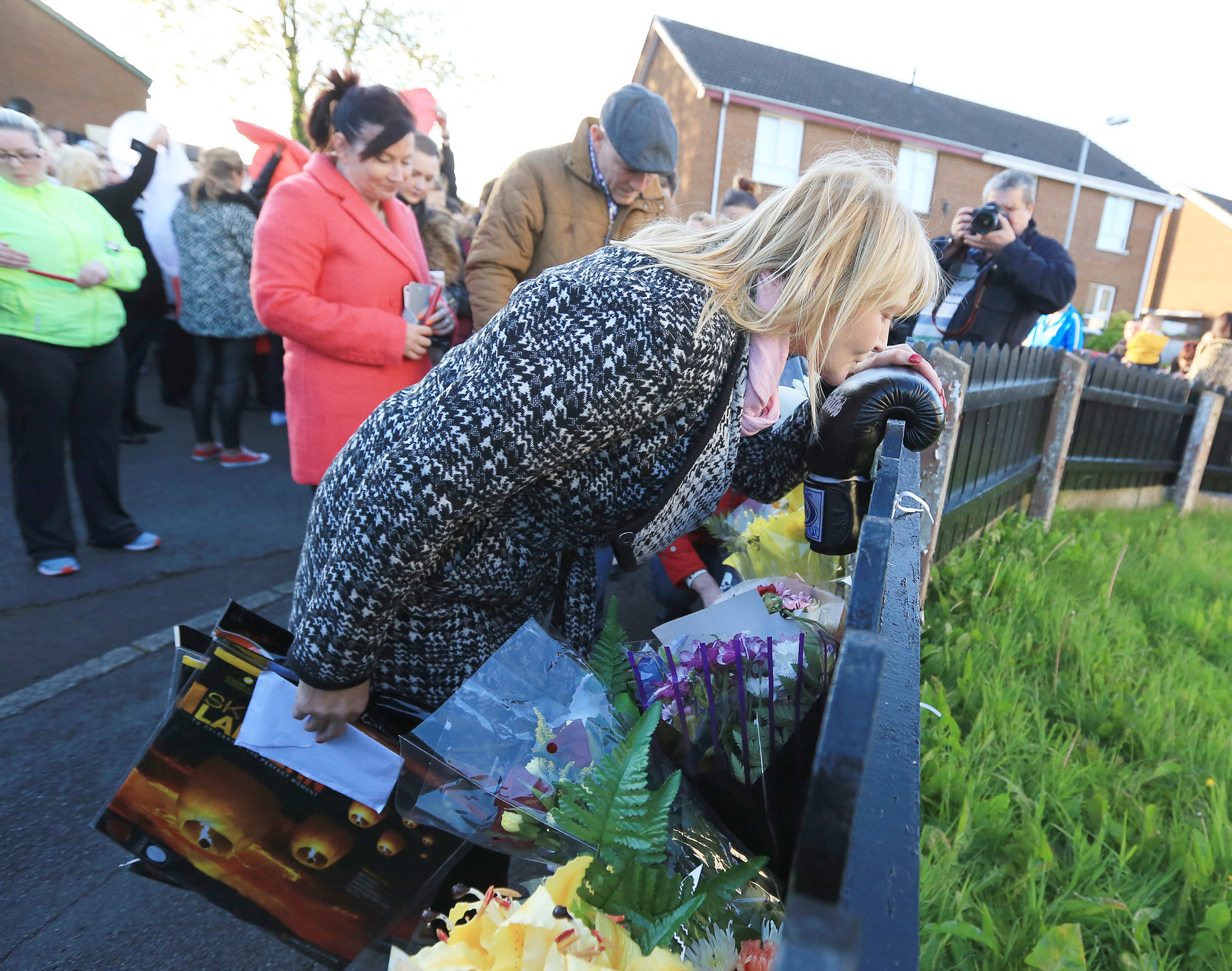 Eamonn Magee Jnr’s mother Mary kisses a single boxing glove left near the scene of the killing while his dad Eamonn Snr bows his head. Pic by Jim Corr