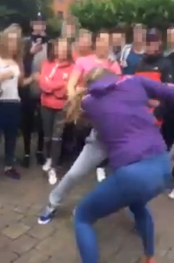 The girls, one from Lenadoon and one from the Shankill, attack each other in a circle formed by a crowd of youths