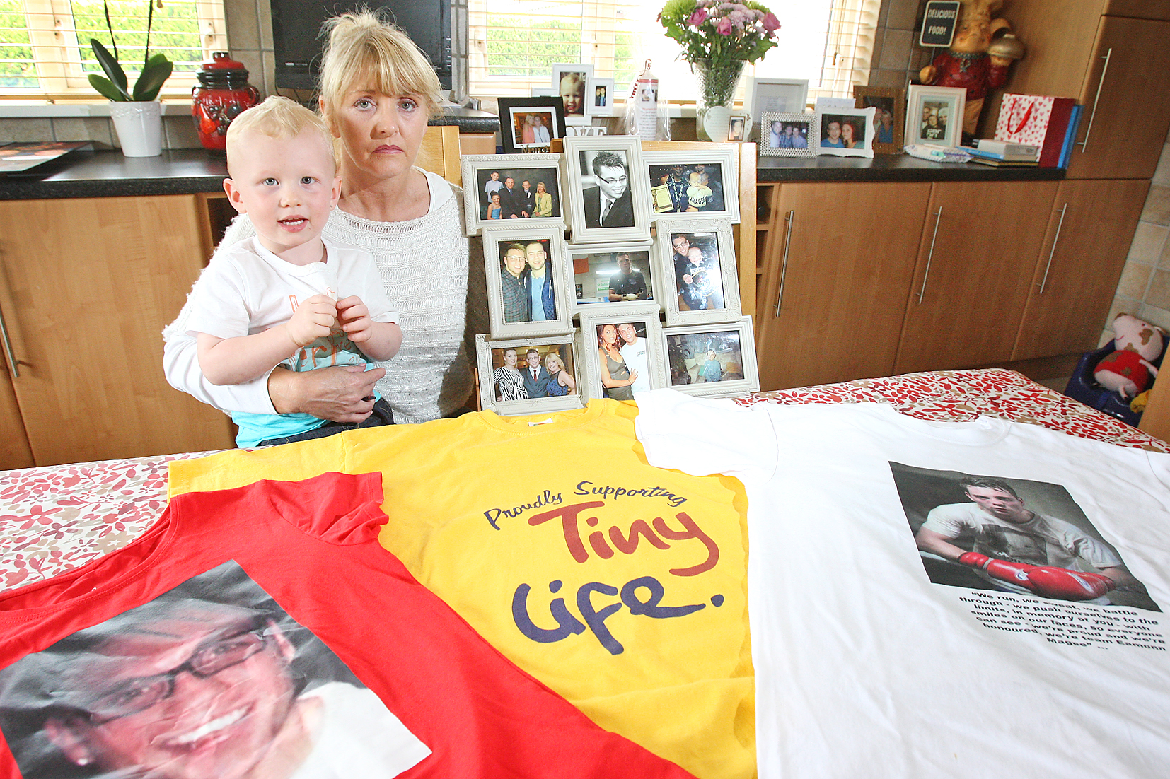 Mary Magee and her grandson Cormac with photographs of Eamonn