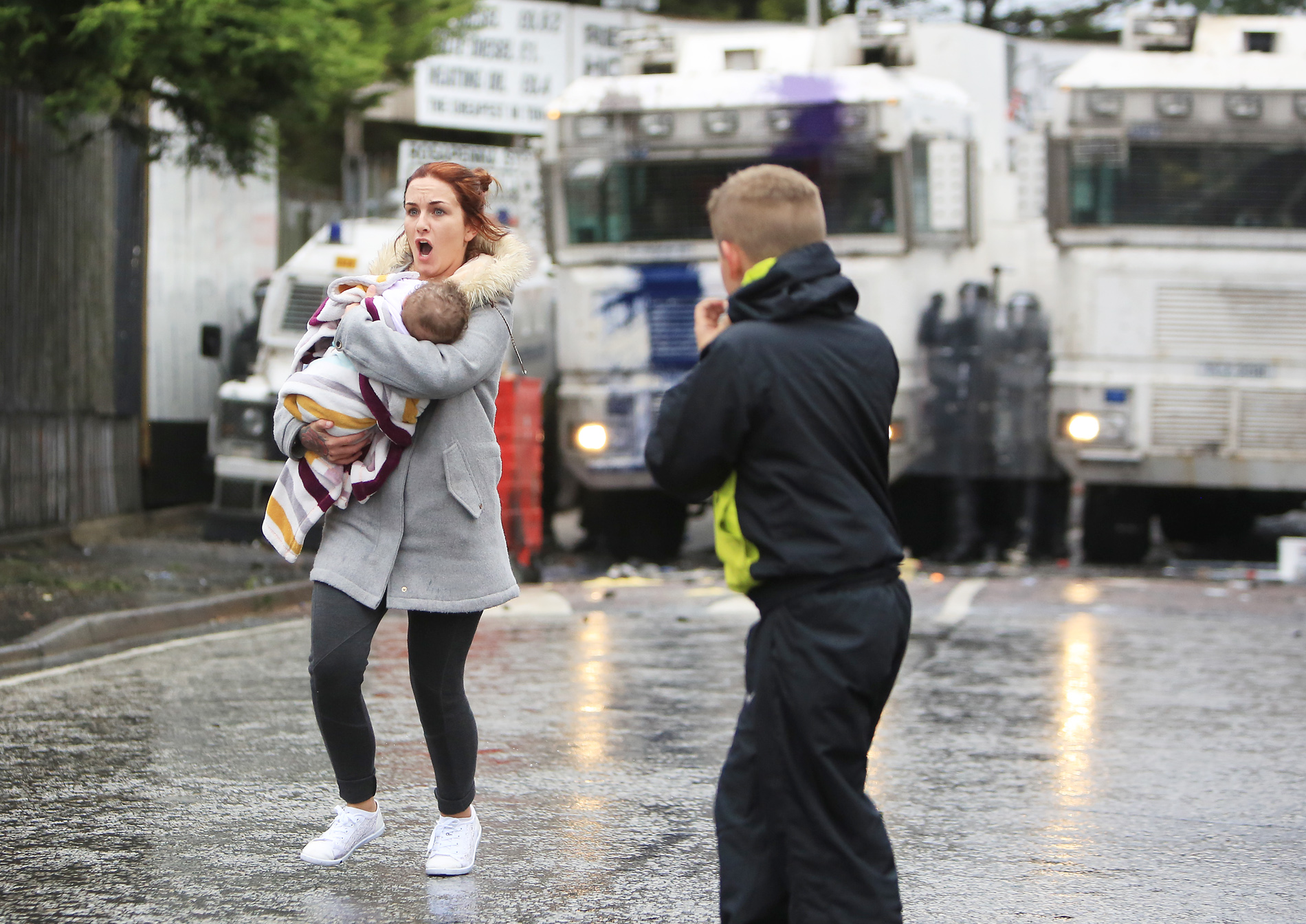 A distressed young mother attempts to make her way to safety with her baby during trouble in North Belfast 