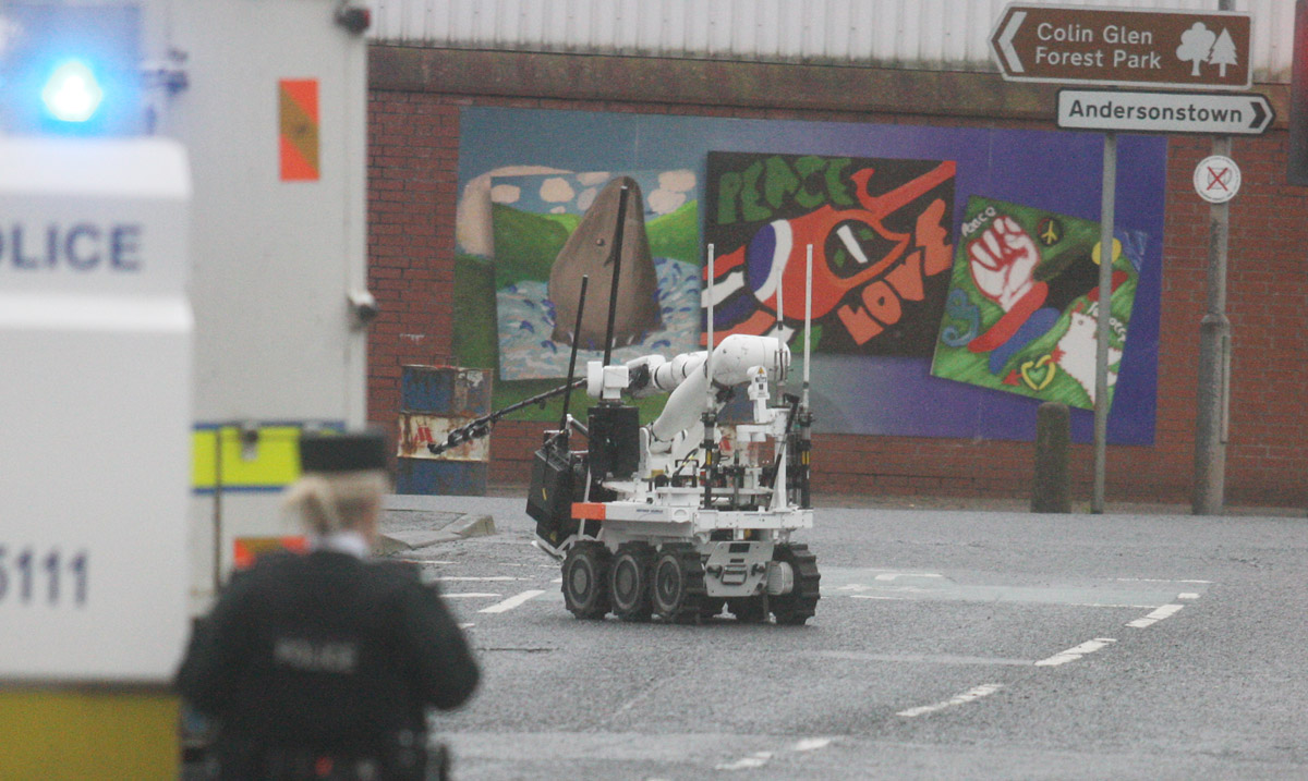 A robot examines a suspicious device outside Woodbourne PSNI station