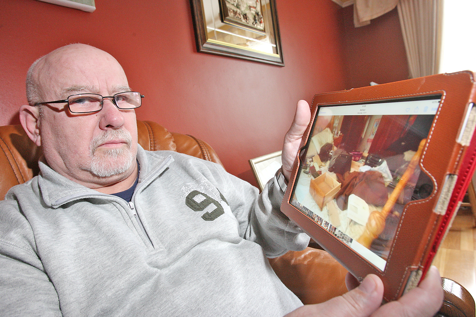 Devastated: Tony Gibson with an image of the ransacked bedroom on his iPad