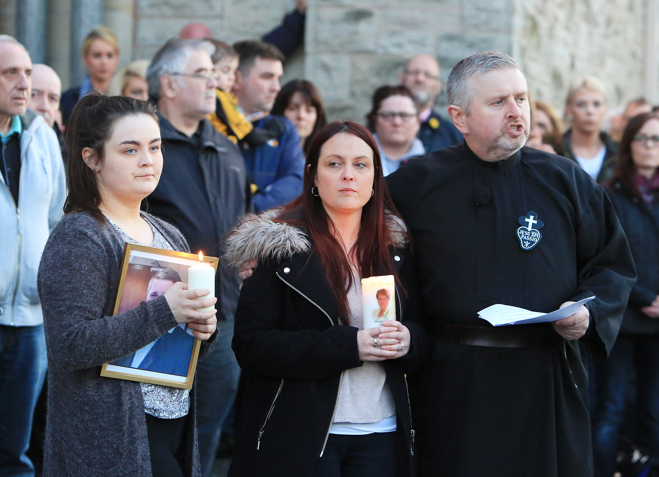 Michael McGibbon\'s wife Joanne McGibbon and daughter Seana with Fr Gary Donegan at the vigil in the grounds of Holy Cross Church, Ardoyne