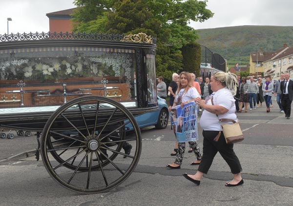 Family members lead the funeral cortege as it makes its way through Turf Lodge yesterday