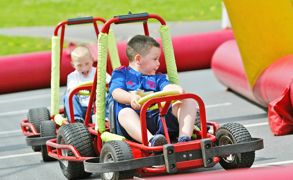 Ruari Fitzsimons takes AJ Harper on the back straight during a Falls Youth Providers Family Fun Day in Dunville Park as part of the Falls Summer Scheme
